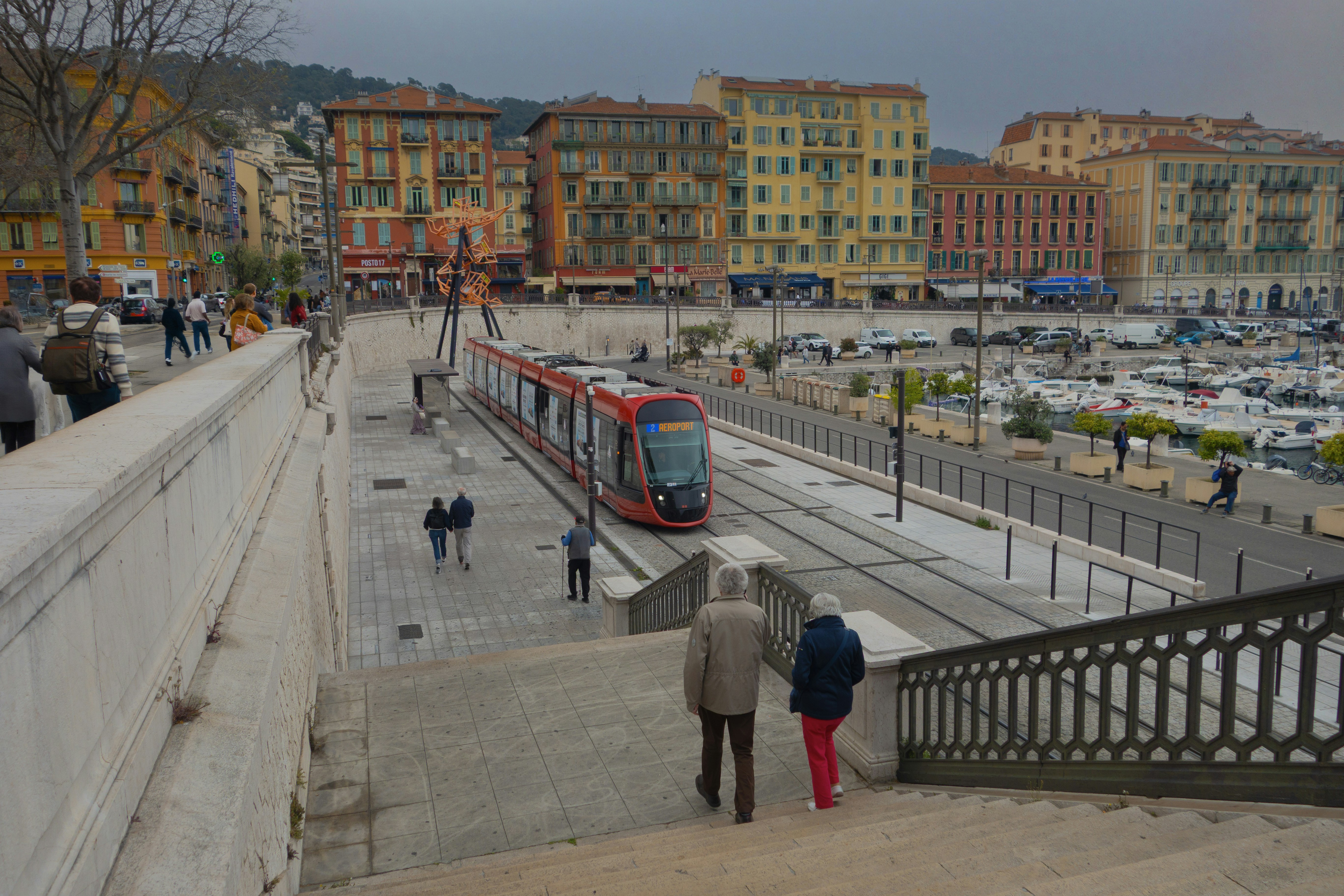 A red tram travels along a coastal city.