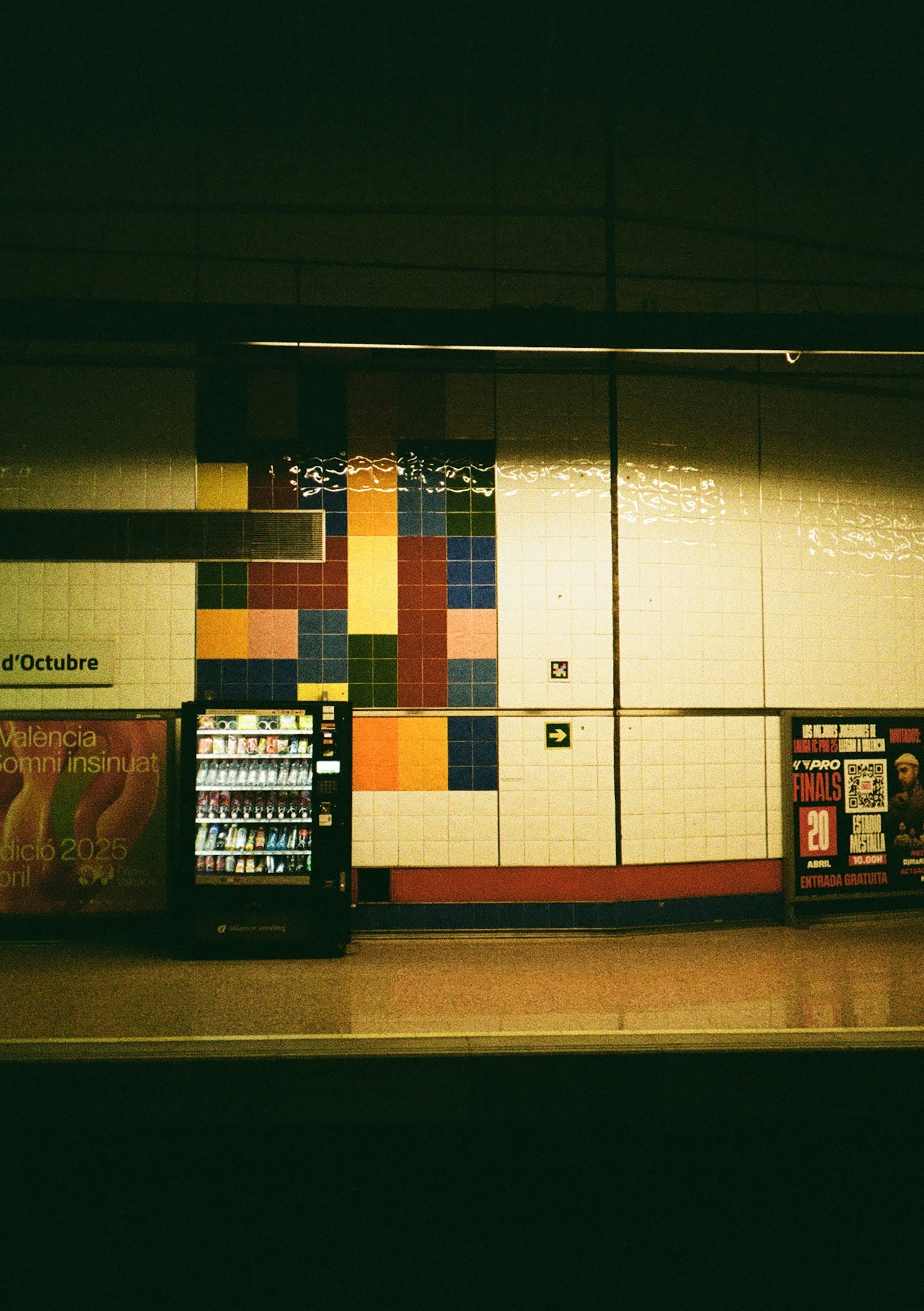 A vending machine stands at a train platform.