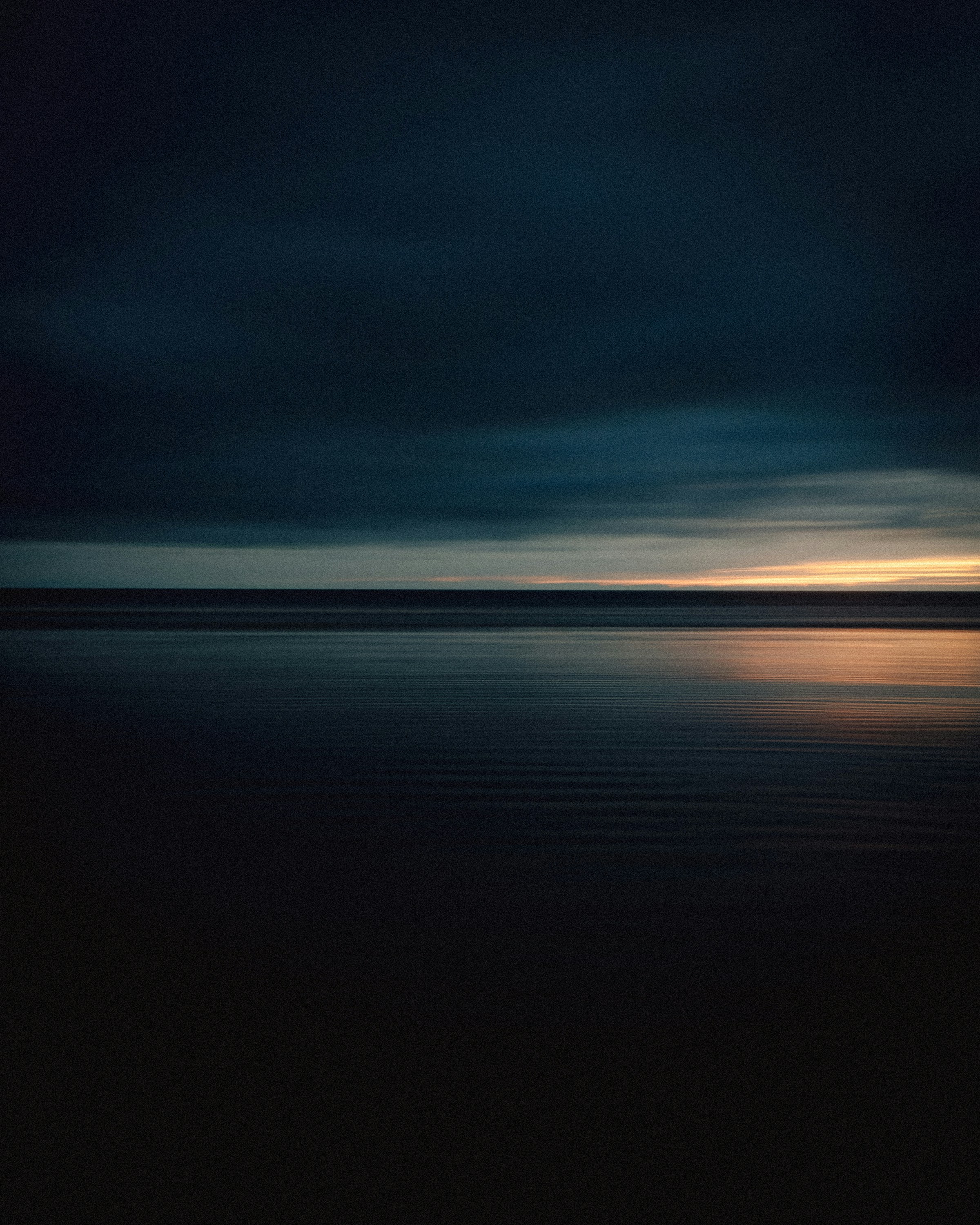 Dark sky reflects on calm water.