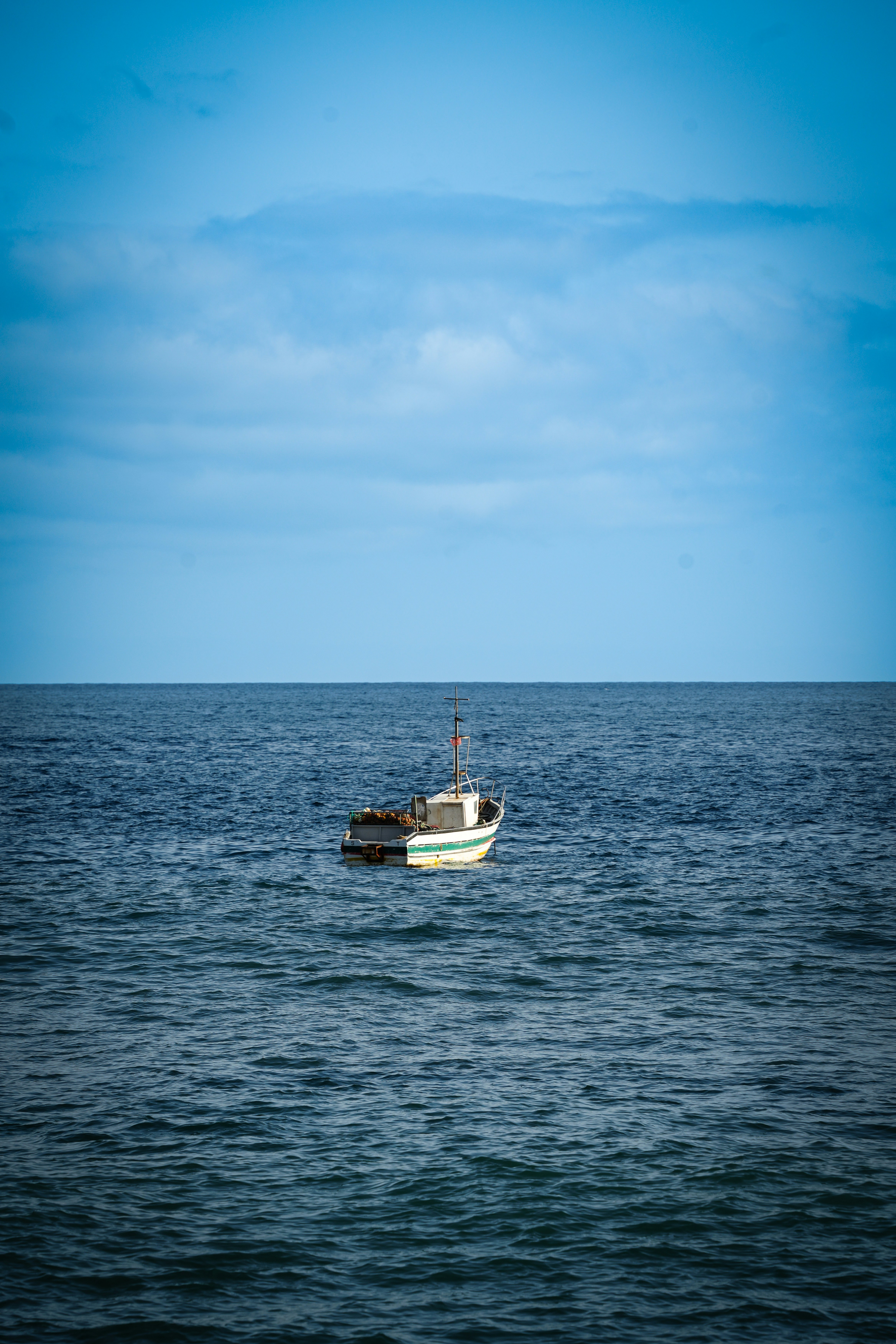 A small boat drifts on the vast ocean.