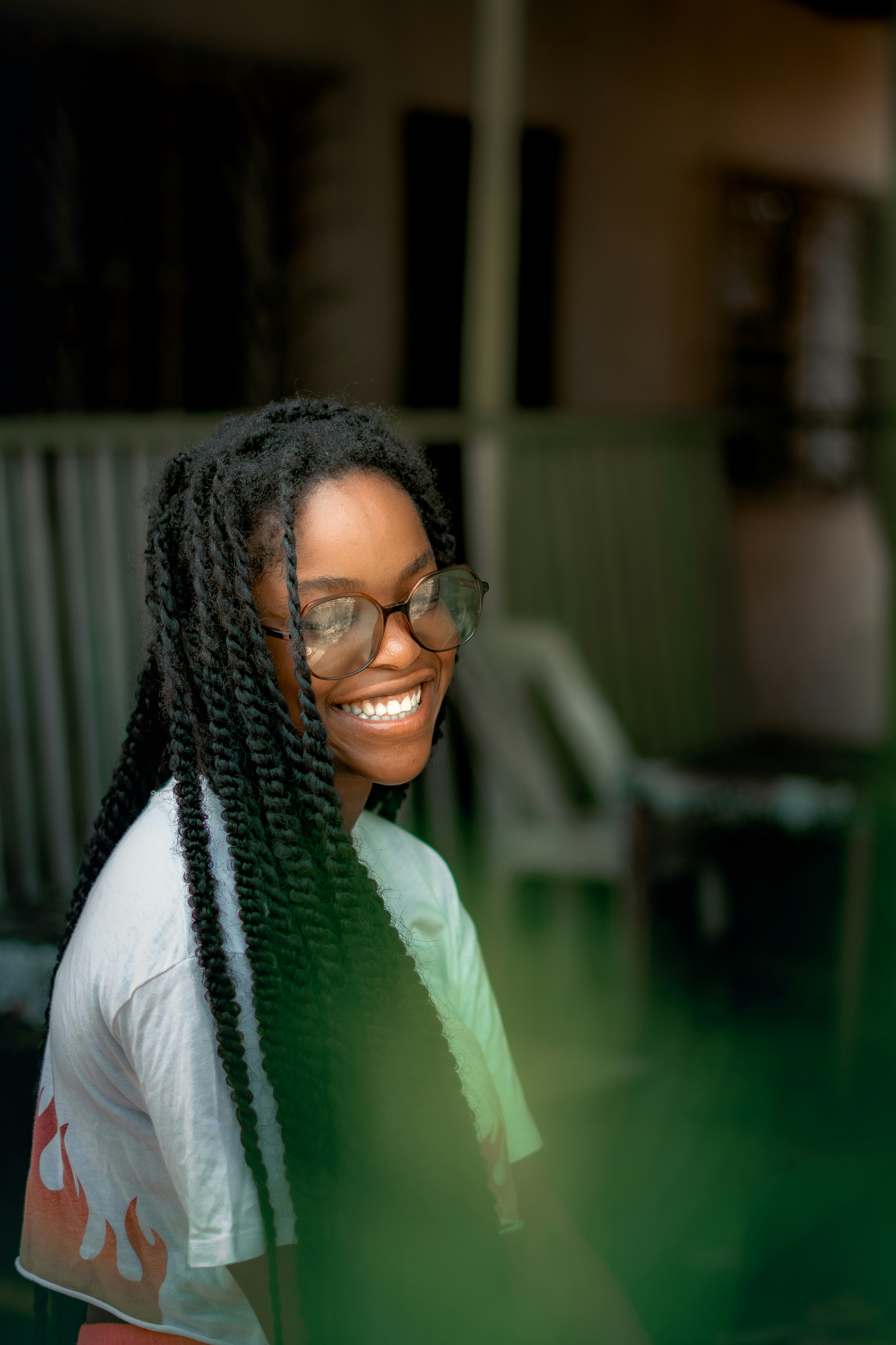Smiling woman with glasses and braided hair.