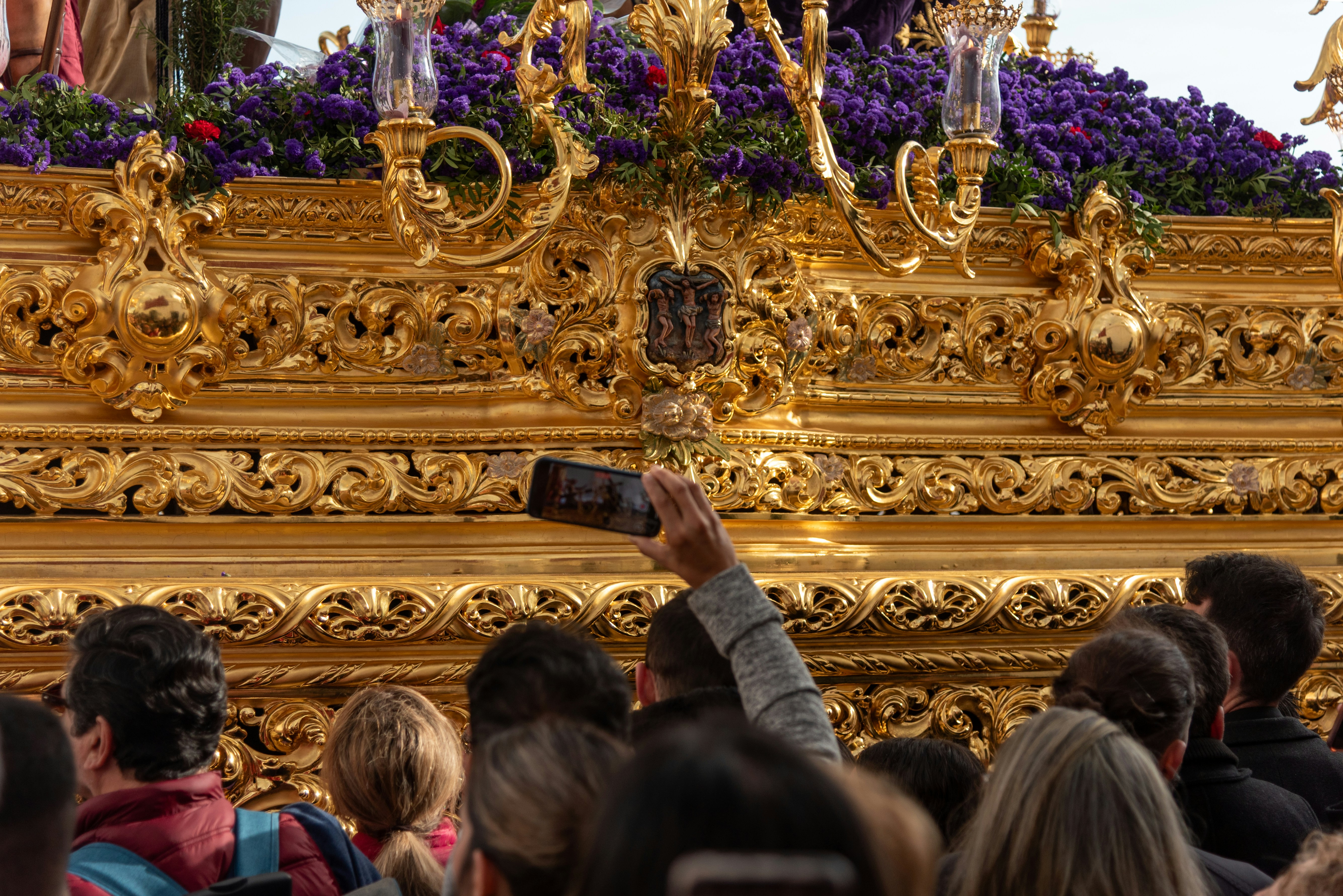 People are taking photos of a golden religious float.