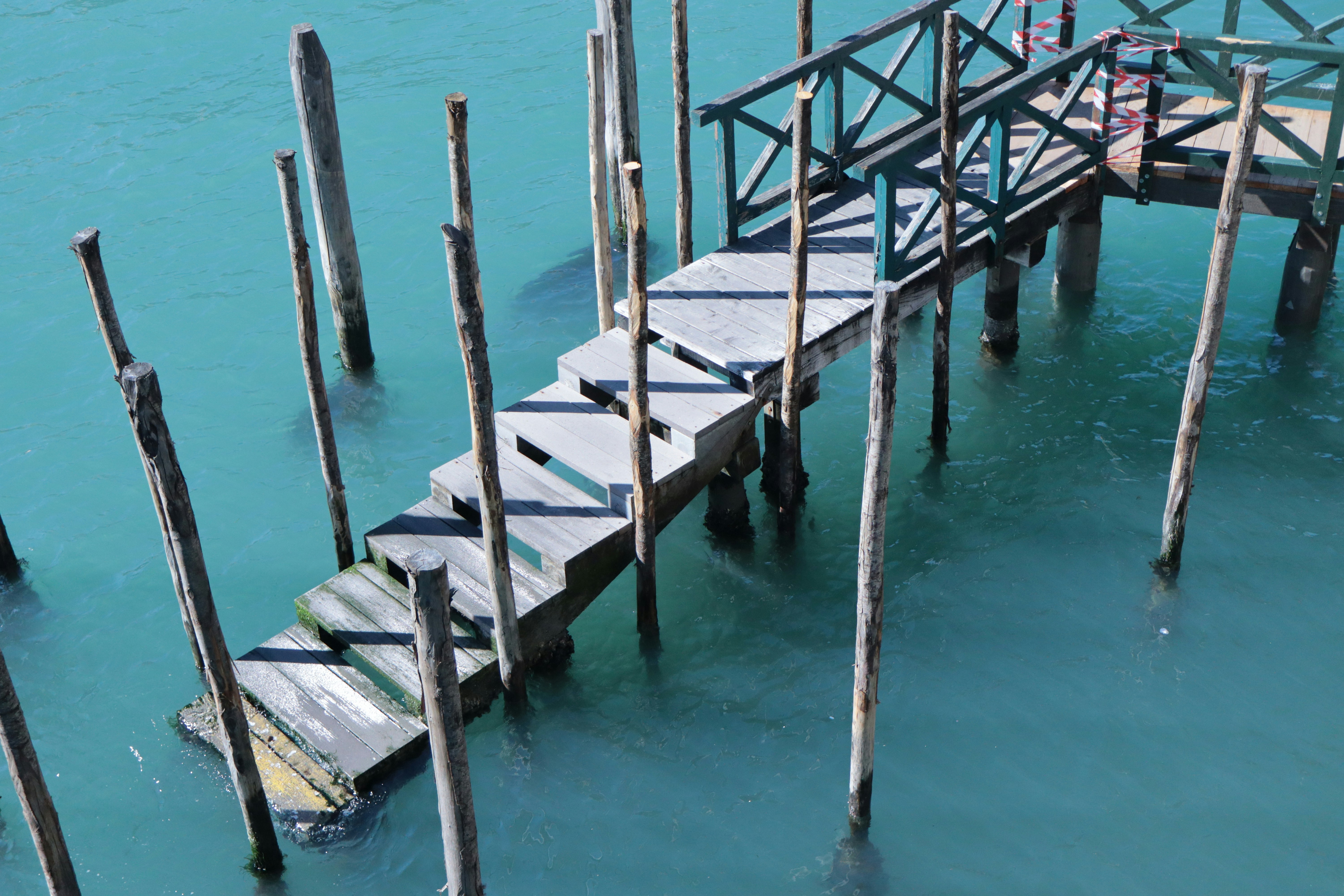 Wooden pier and stairs descend into turquoise water.