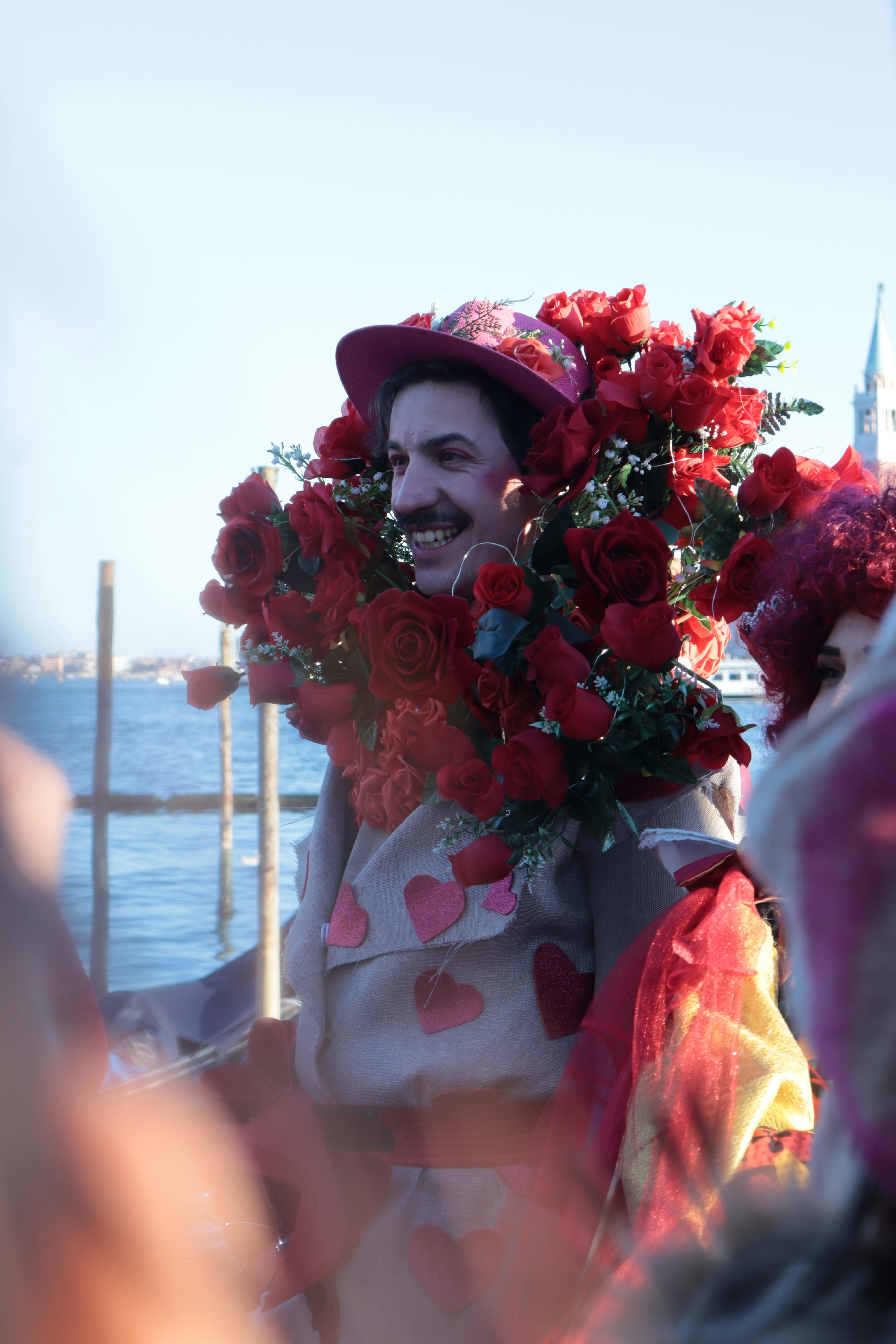 A smiling man wears a floral hat and collar.