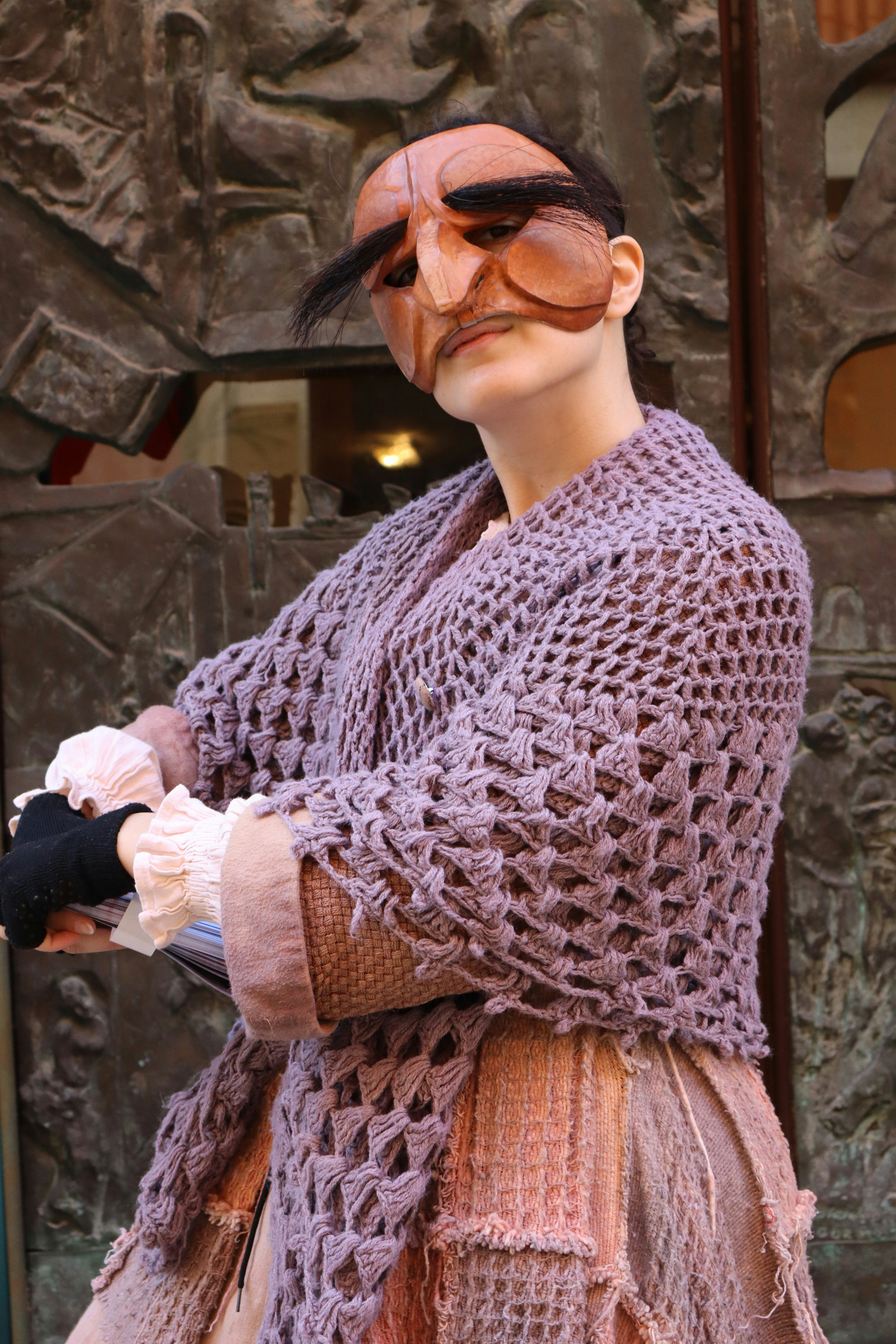A person wearing a mask and shawl poses.