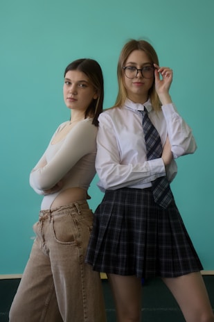 Two young women pose in front of a blue background.