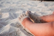 Bare feet resting on white sand.