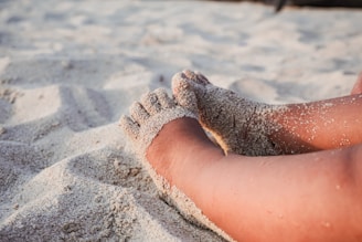 Bare feet resting on white sand.