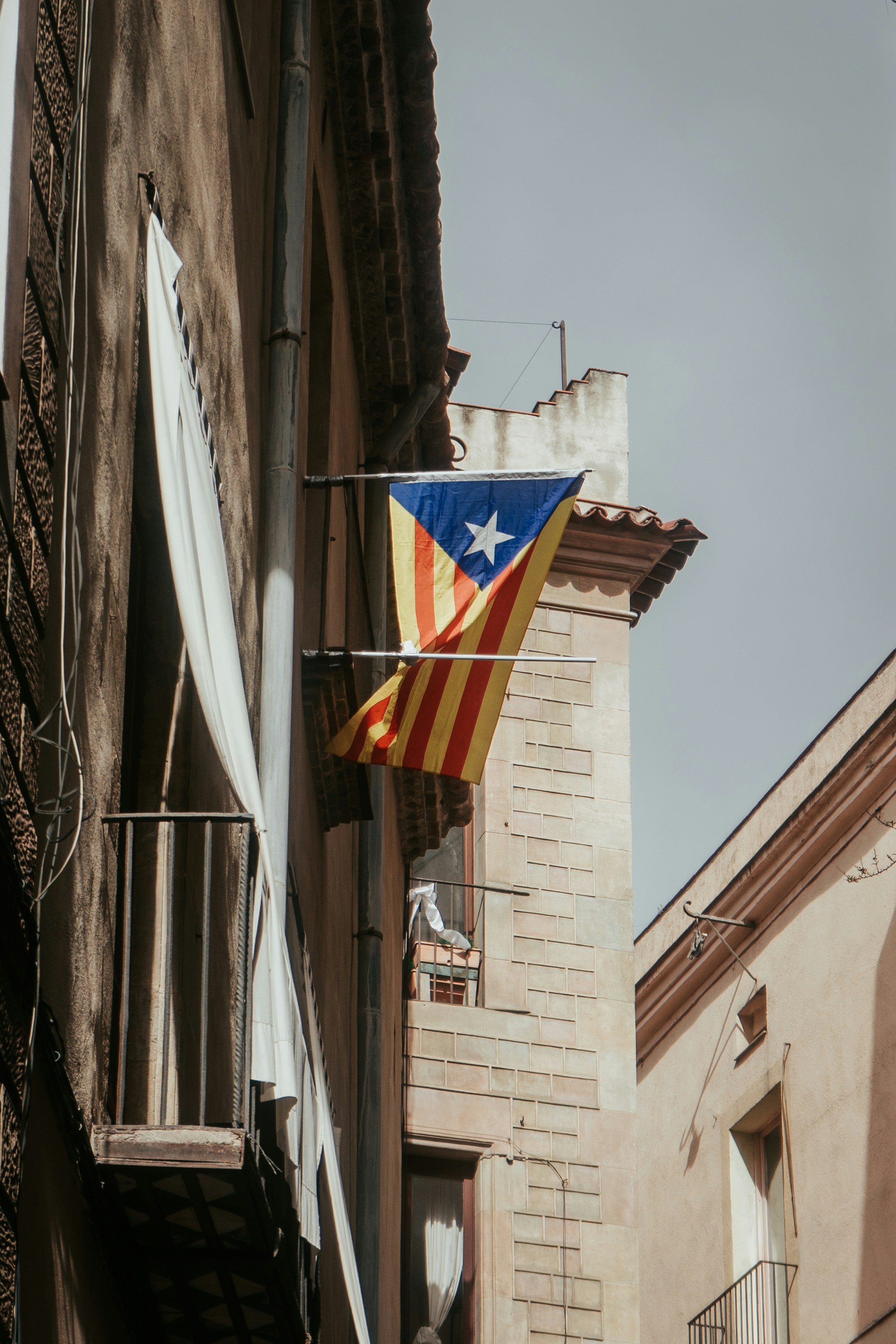 A flag of catalonia hangs from a building.