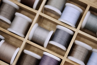 Spools of thread neatly arranged in a wooden box.