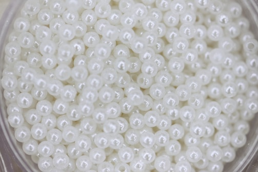 Many small, white pearls are shown in a close up.