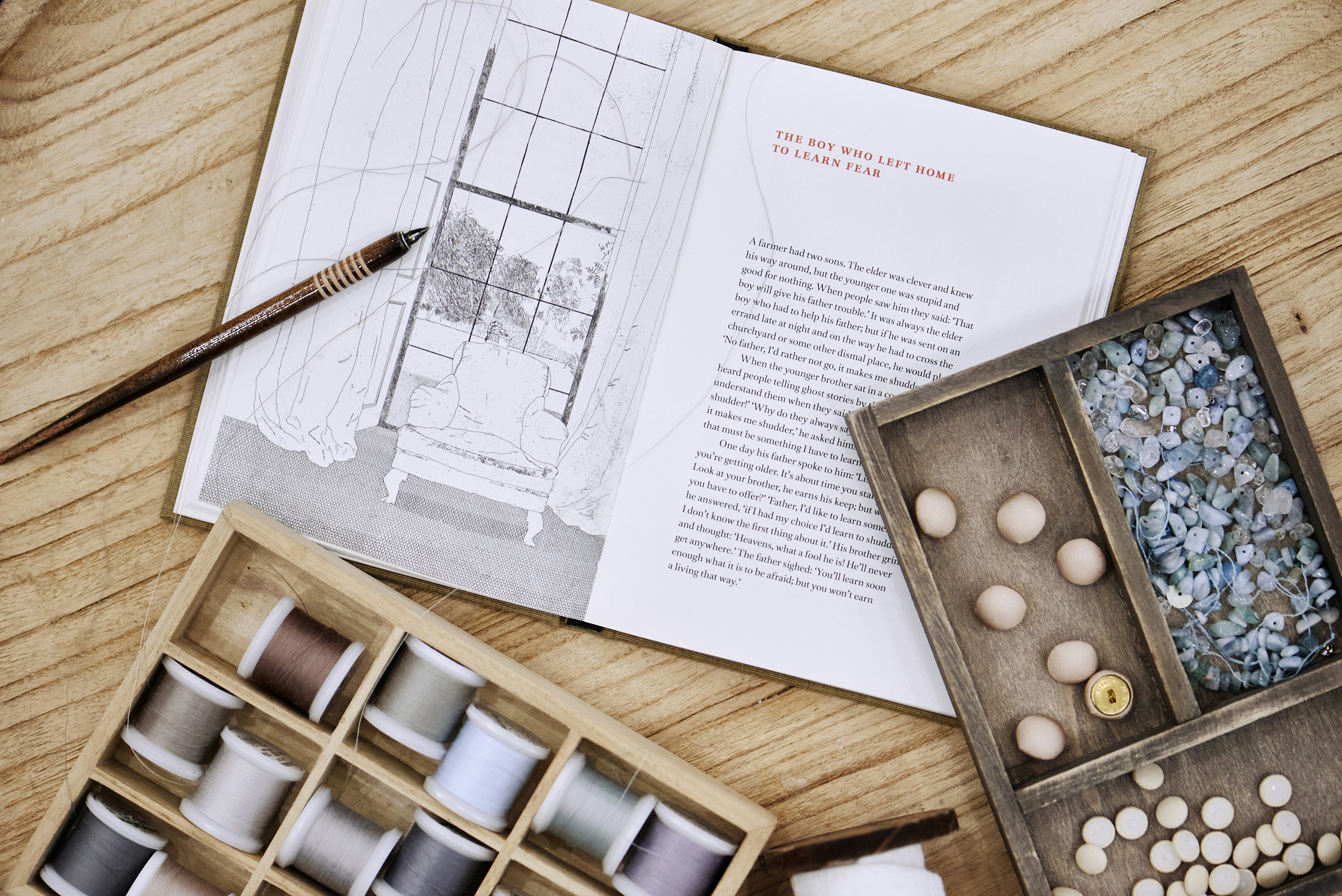 Craft supplies and a book lay on a wooden surface.