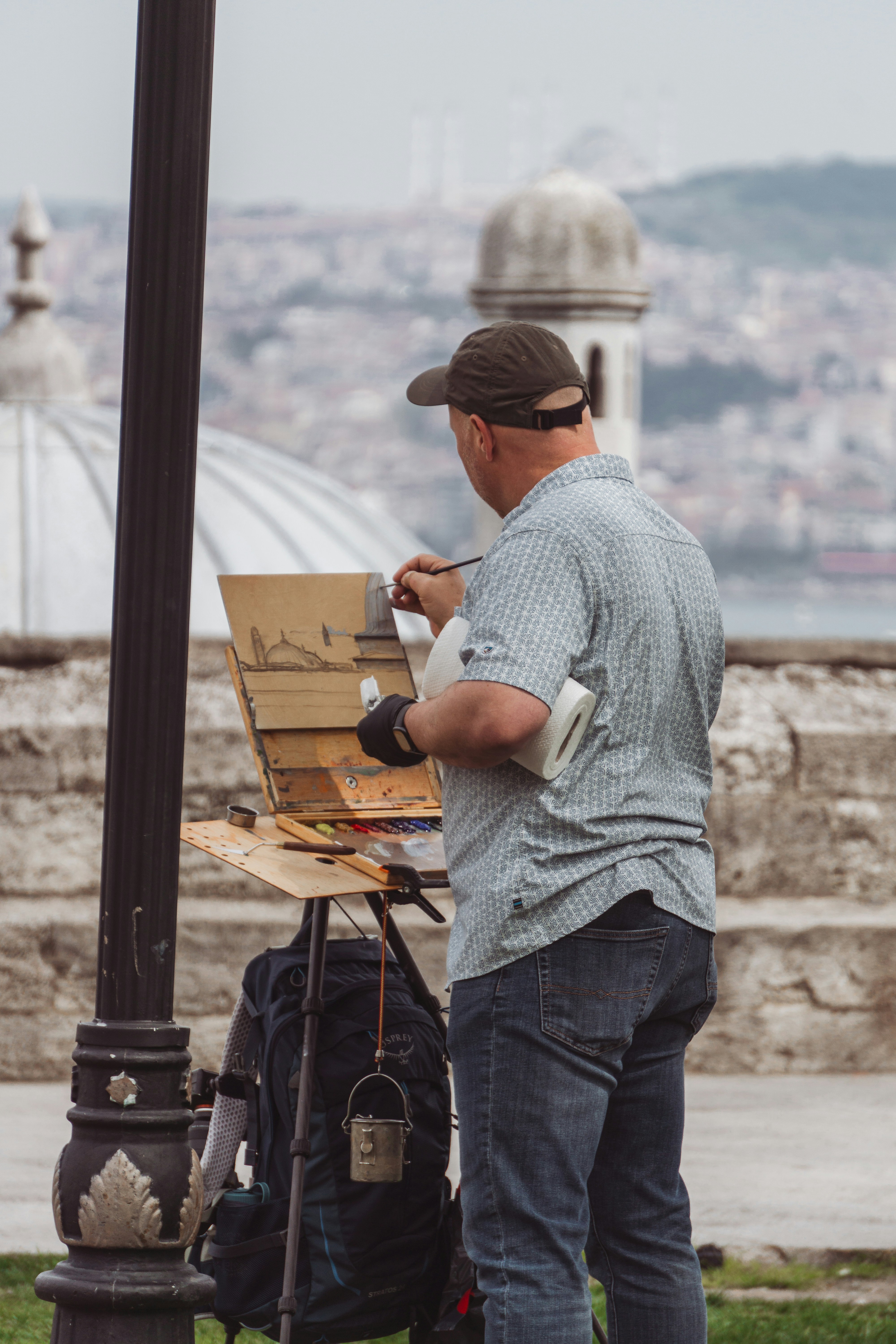 An artist paints outside with a beautiful backdrop.