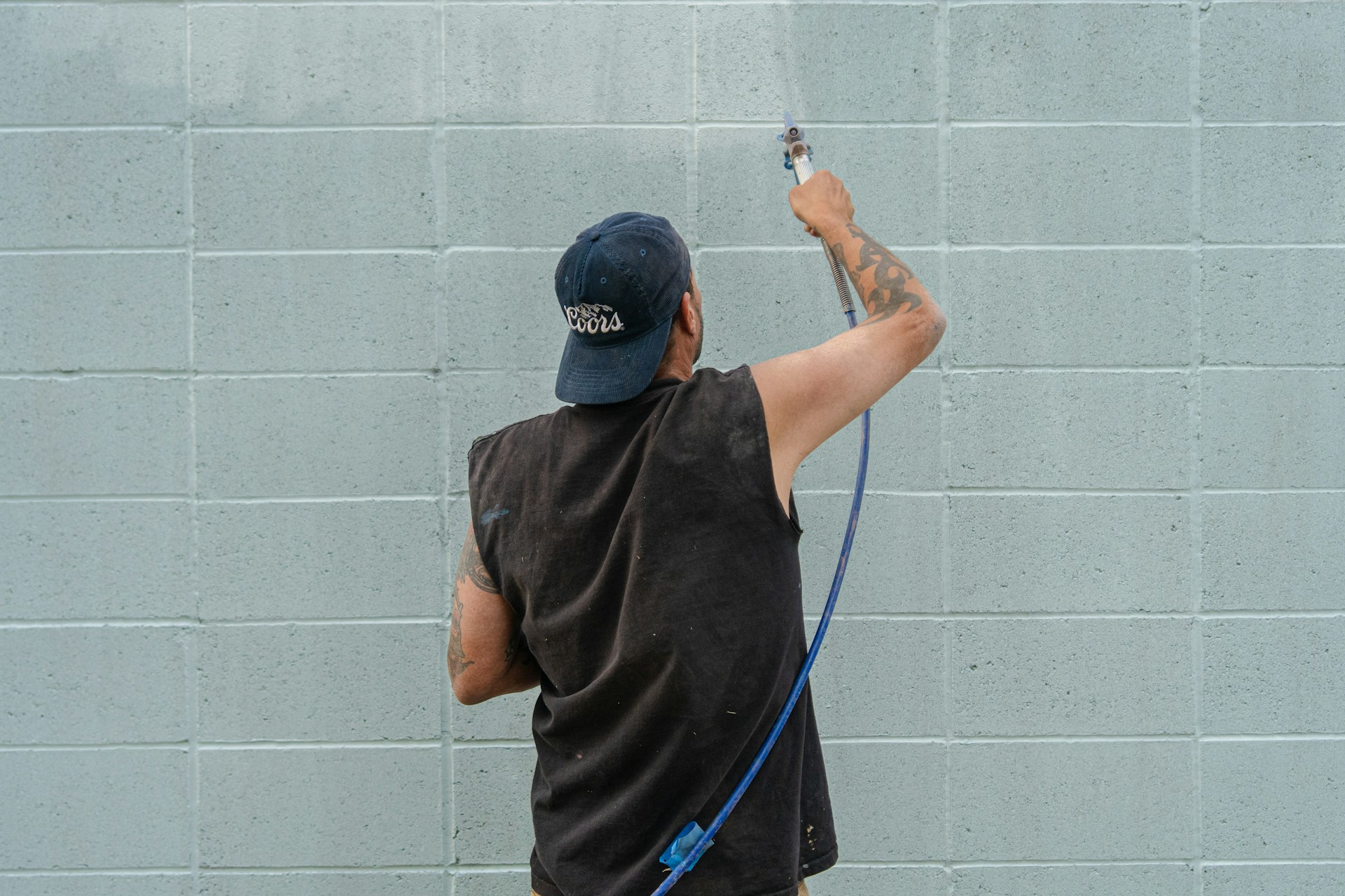 A man is painting a wall with a sprayer.