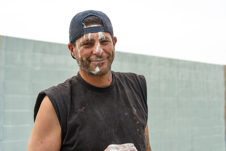Nico Reyes, owner of Ocotillo Painting, grinning with paint on his face after a block-wall job