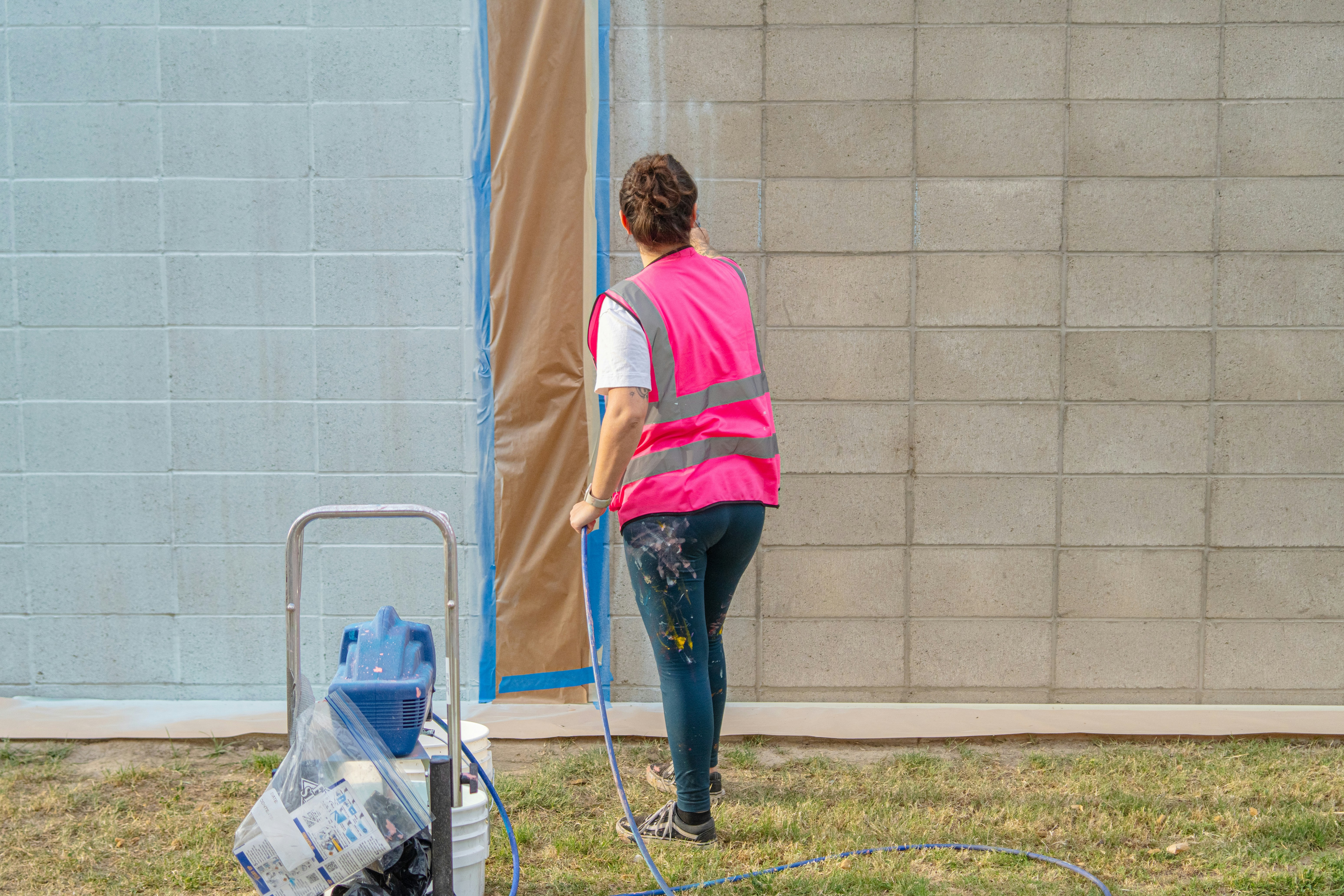 A person is painting a wall with a paint sprayer.