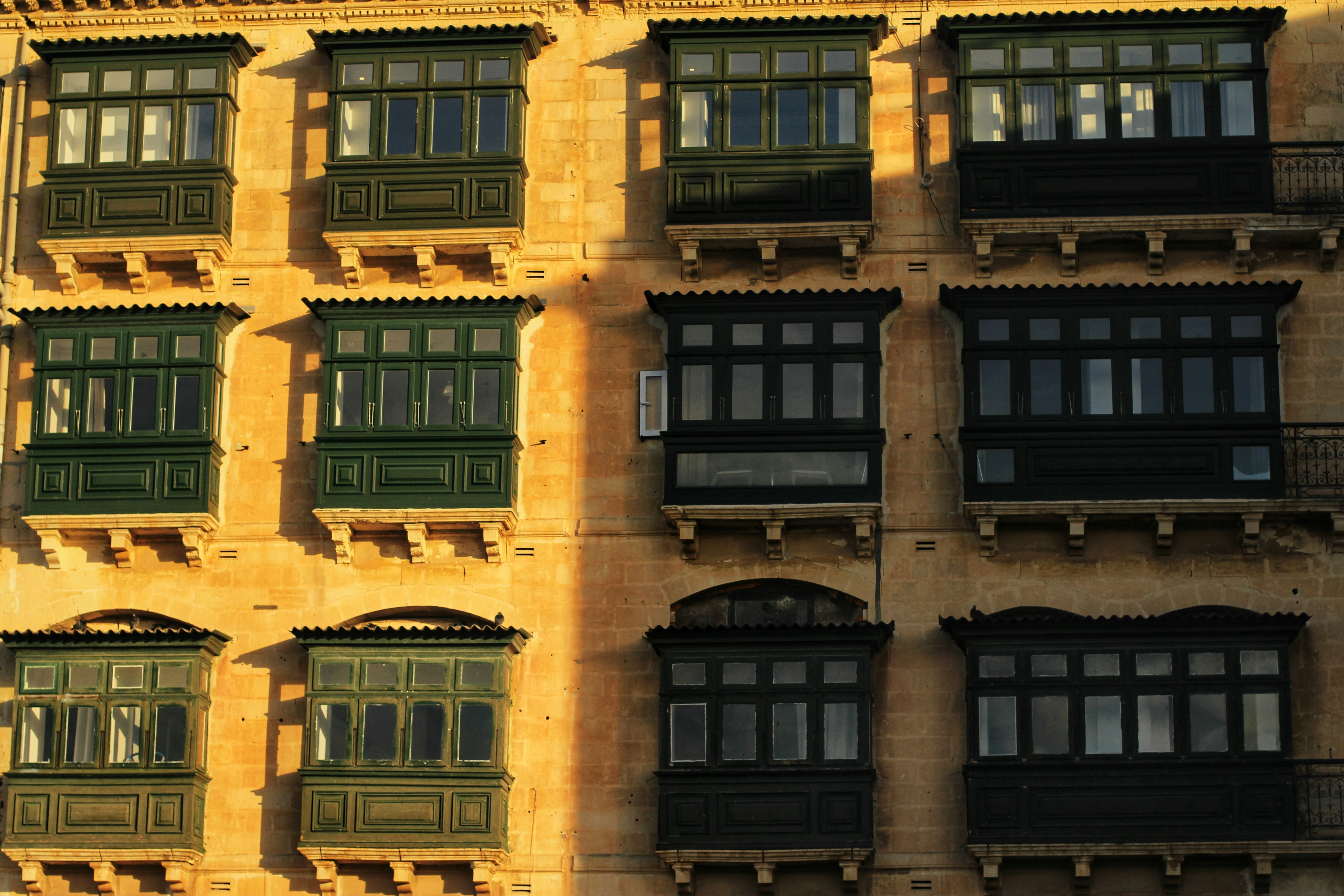Ein Gebäude mit Balkonen in sonniger Fassade.