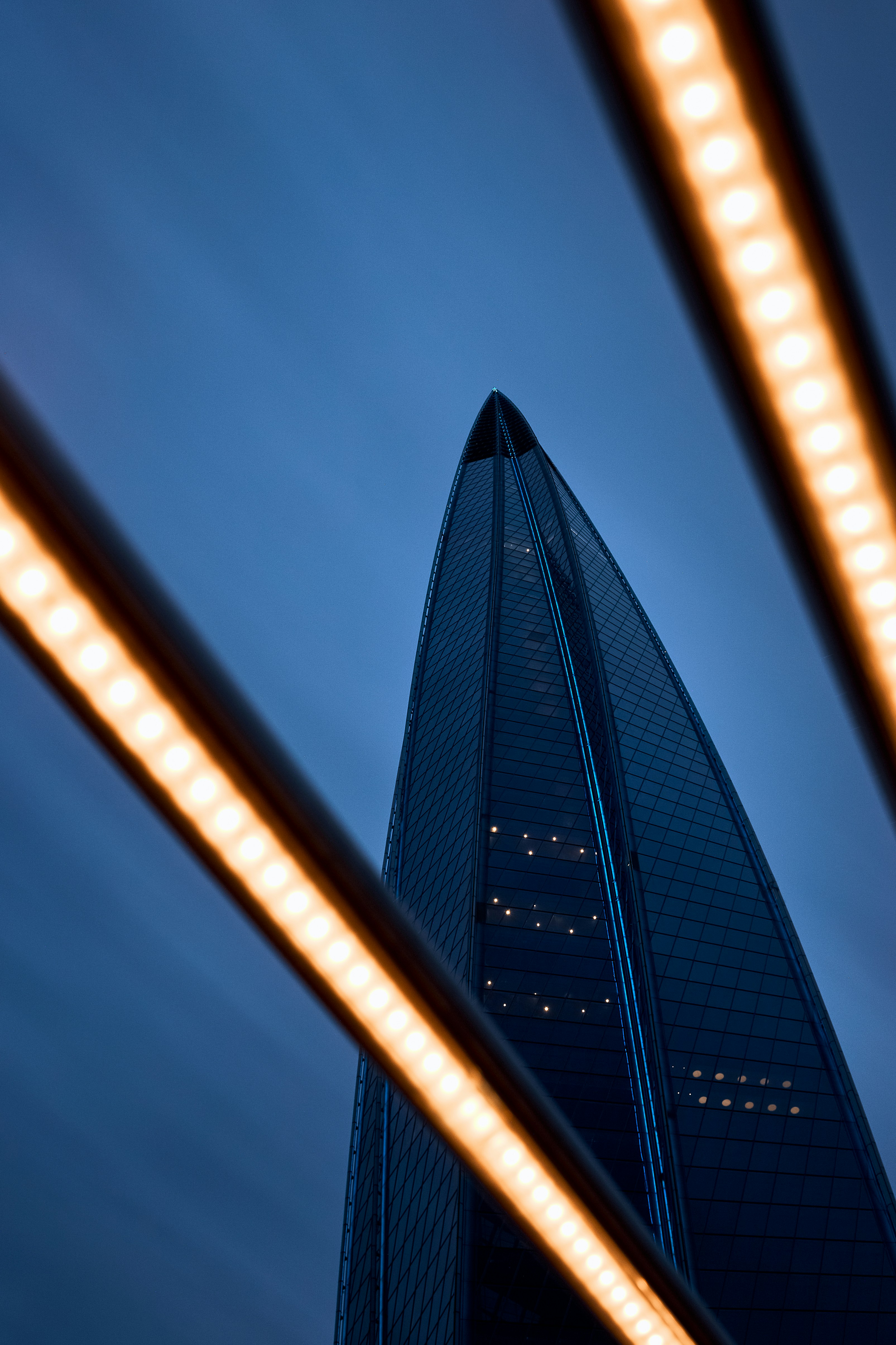 A tall building is viewed through illuminated lights.