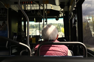 An elderly person rides the bus, looking ahead.