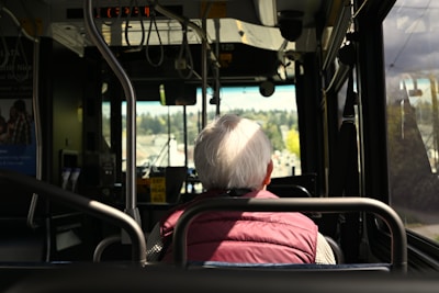 An elderly person rides the bus, looking ahead.