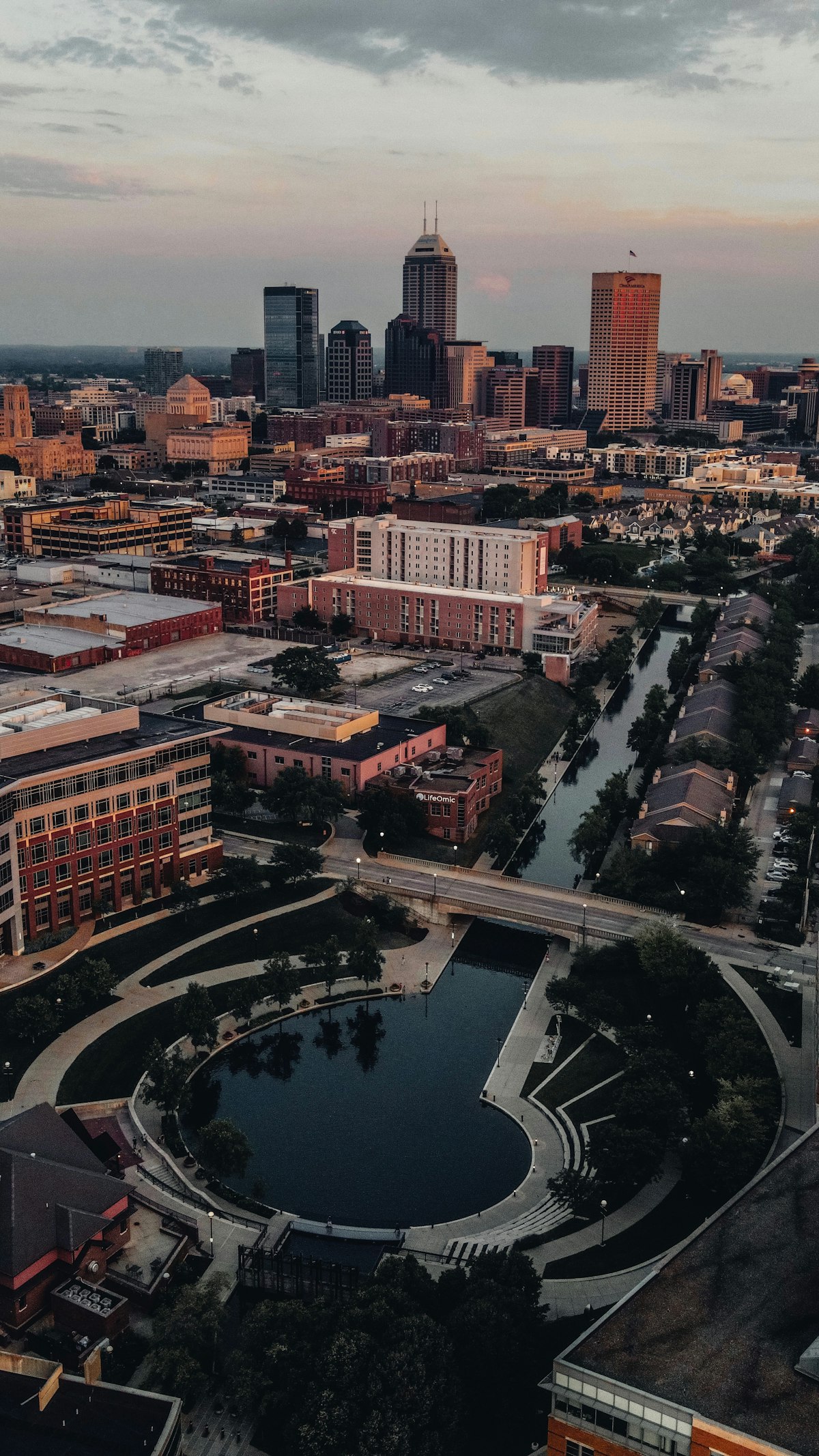 Indianapolis skyline at dusk with illuminated downtown buildings and waterway reflection