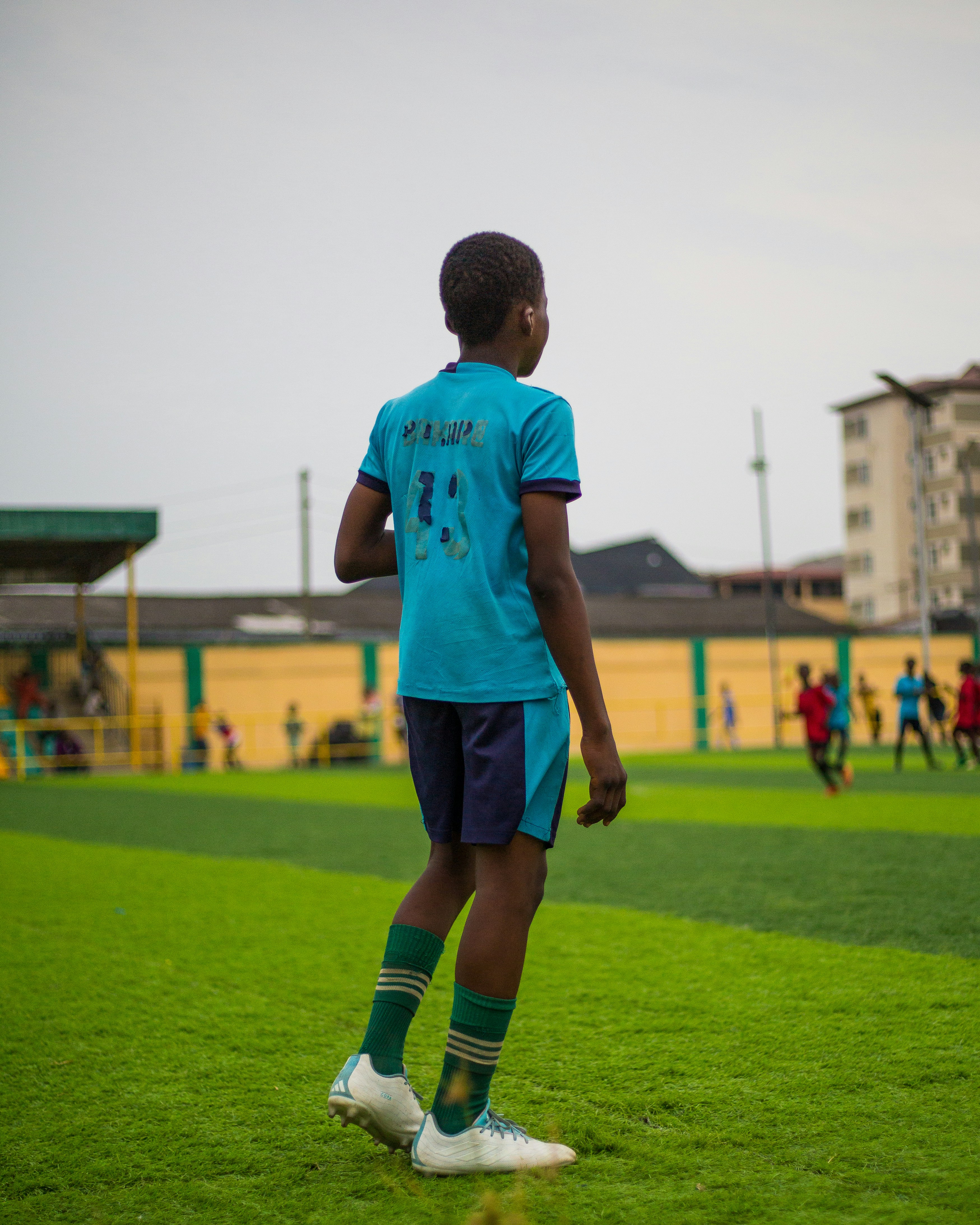 A young boy stands on a soccer field.