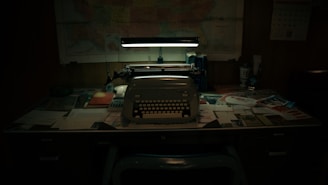 Typewriter sits on a cluttered desk in dim lighting.