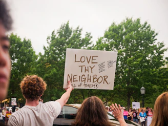 People protest while holding a "love thy neighbor" sign.