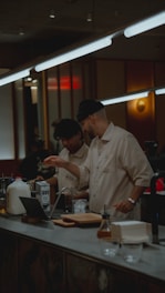 Two baristas interact behind a counter.