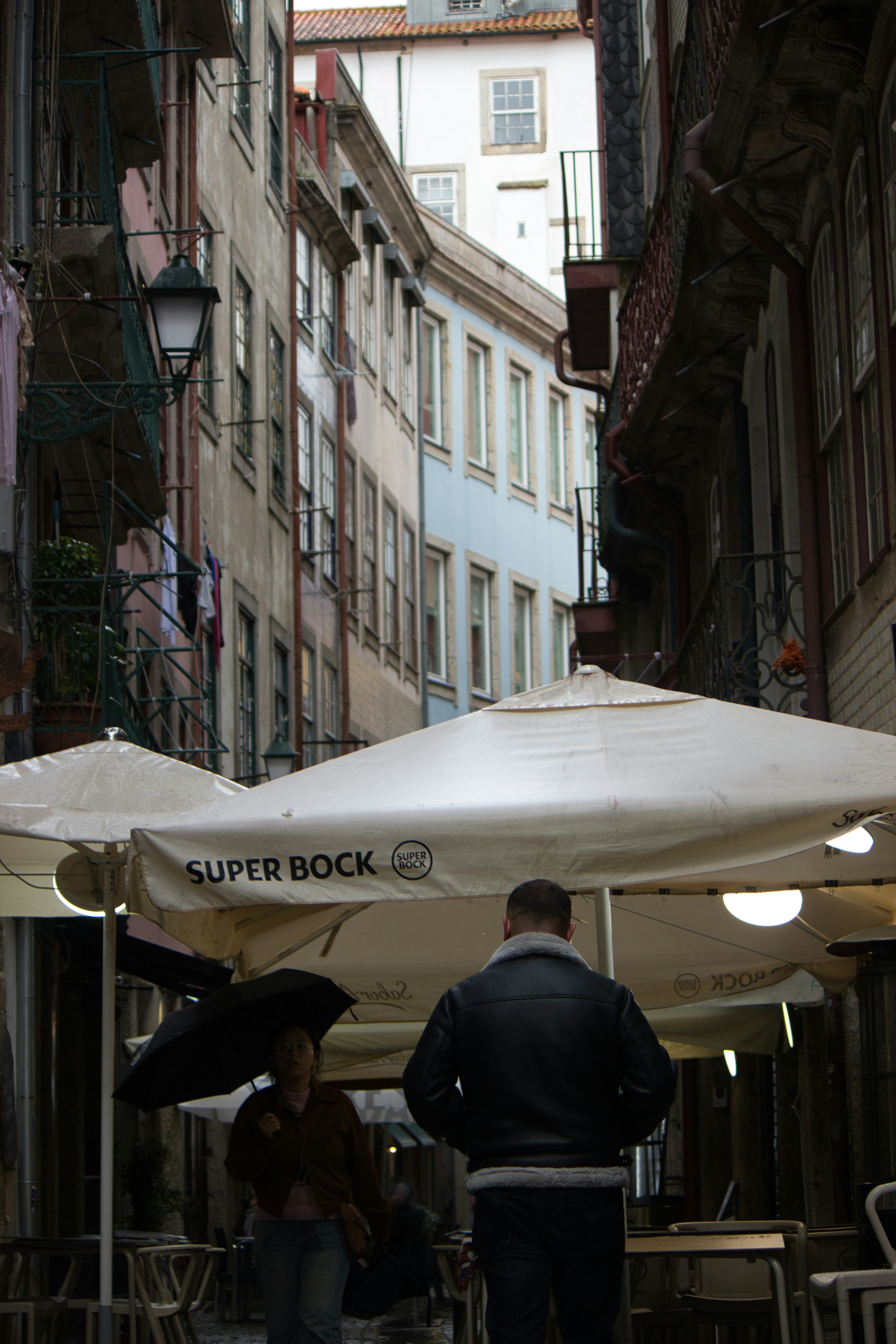 People walk down a narrow, european street.