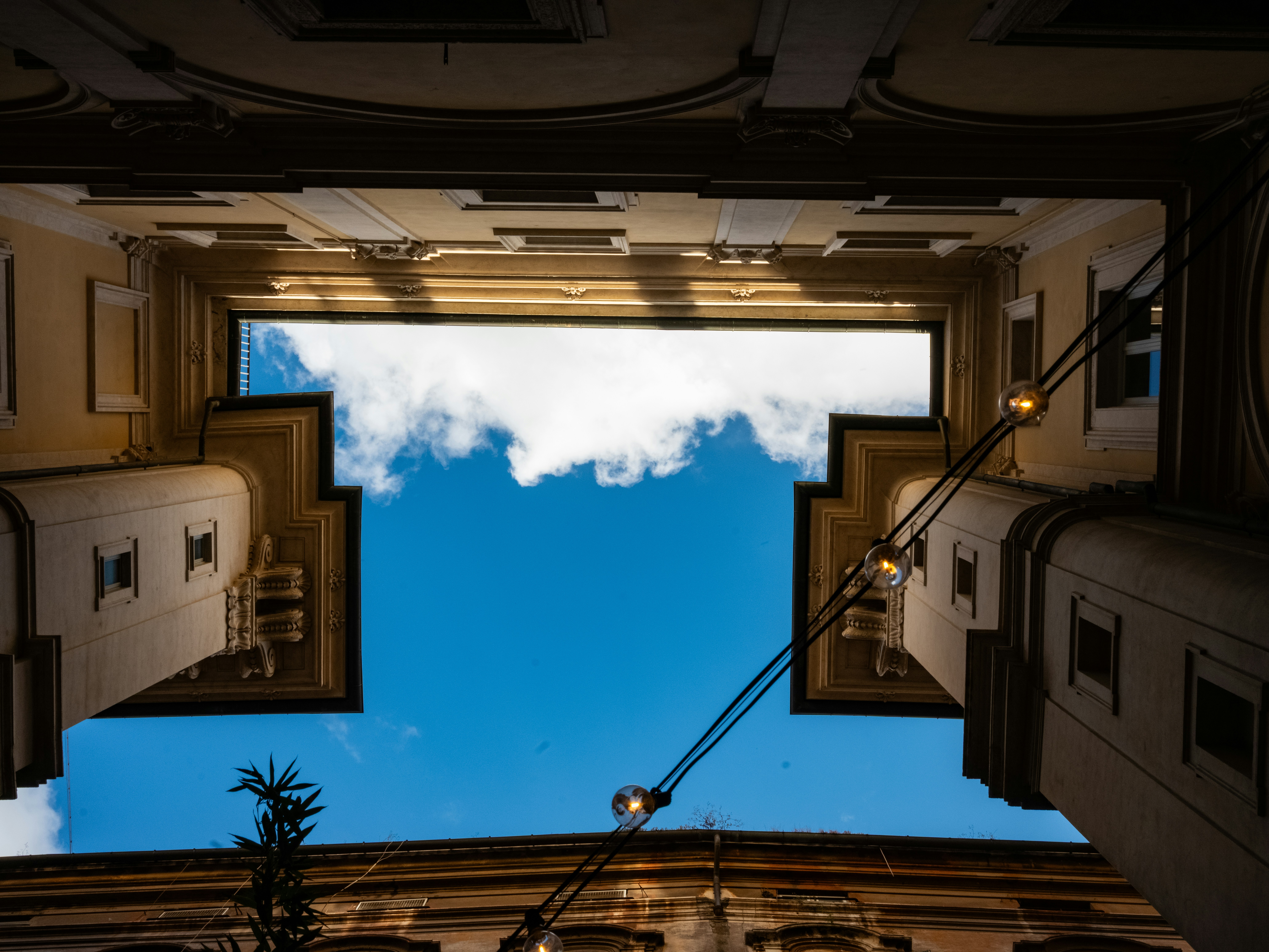 Buildings frame a blue sky with clouds.