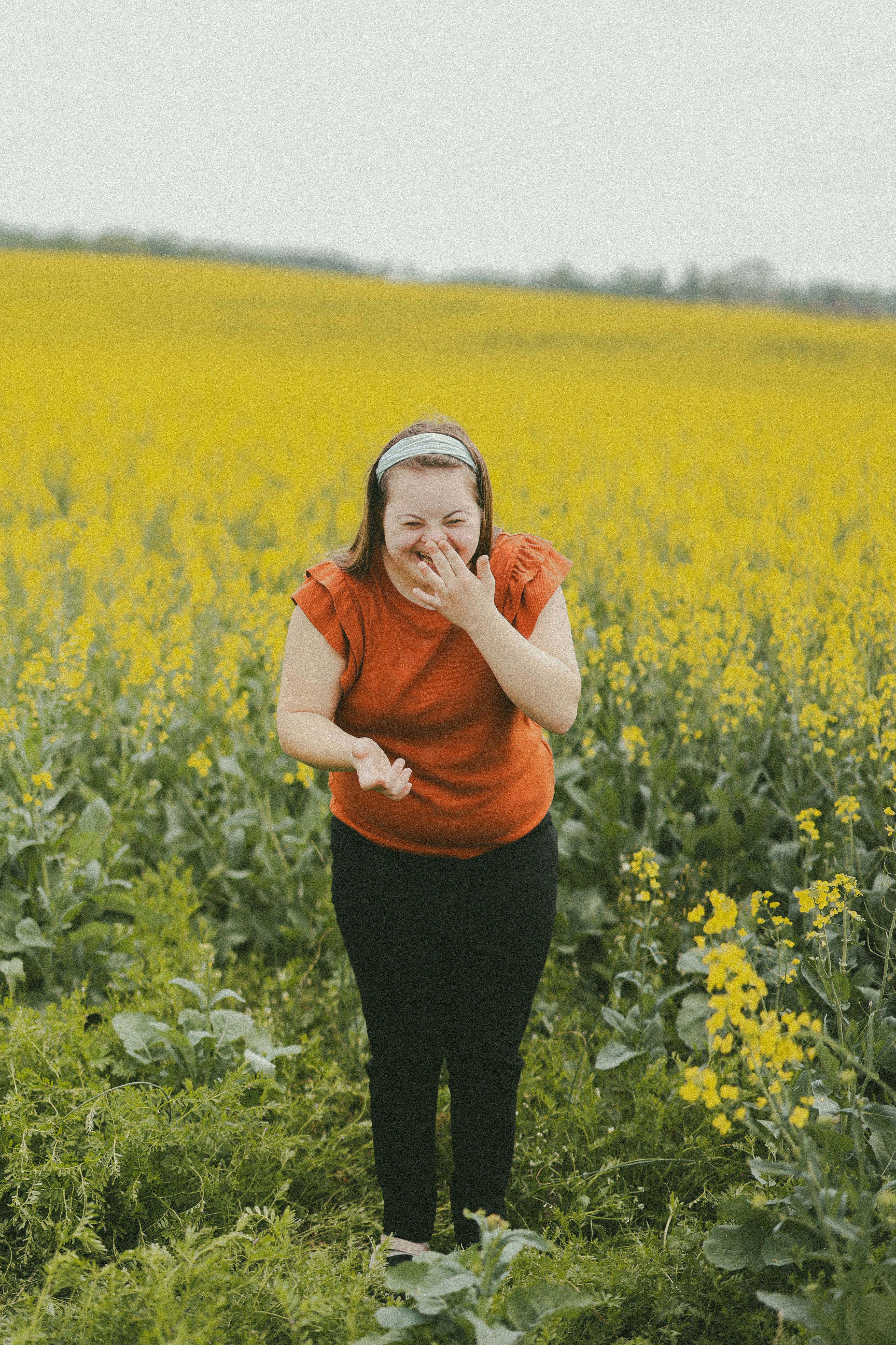 Woman laughs in a field of yellow flowers
