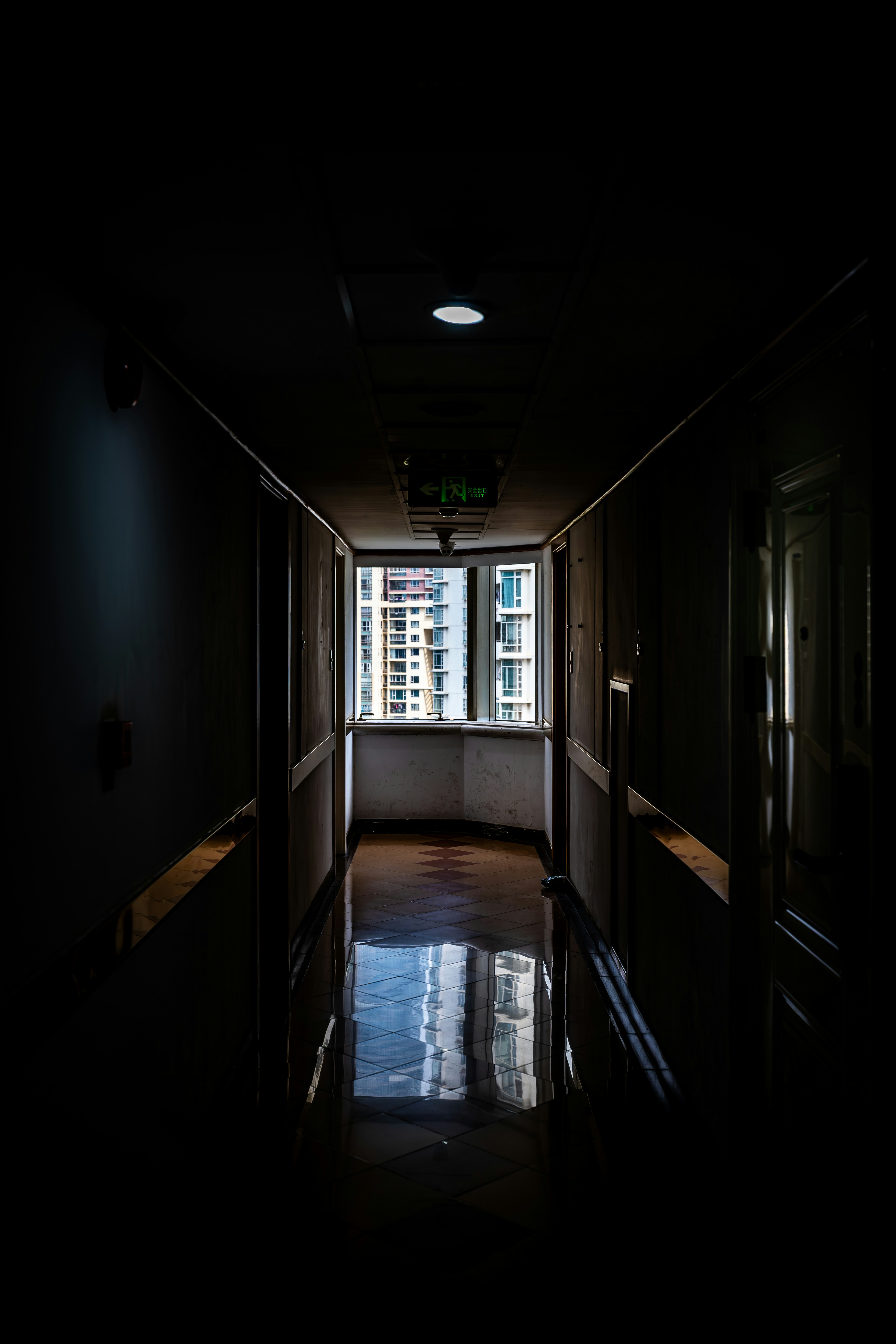 A dark hallway leads to a bright window.