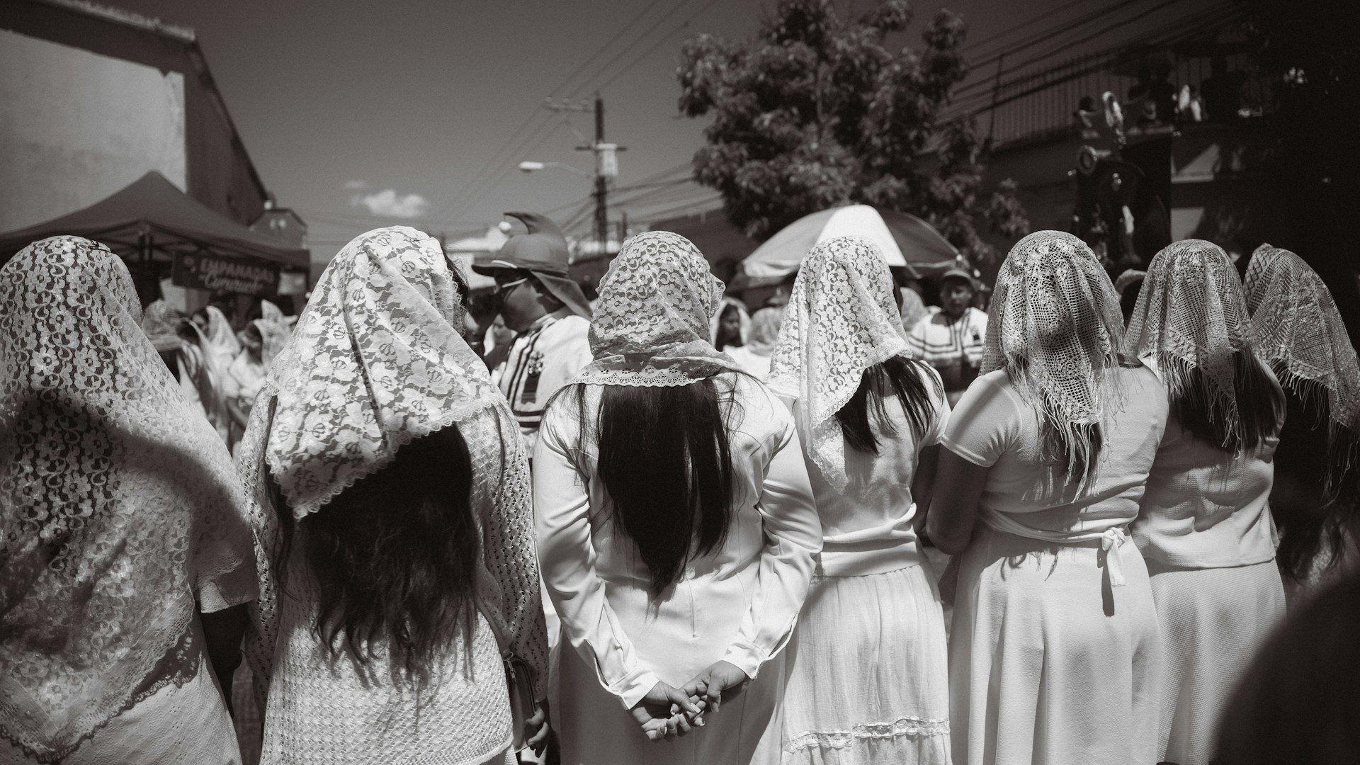 Women in white veils stand together outdoors.