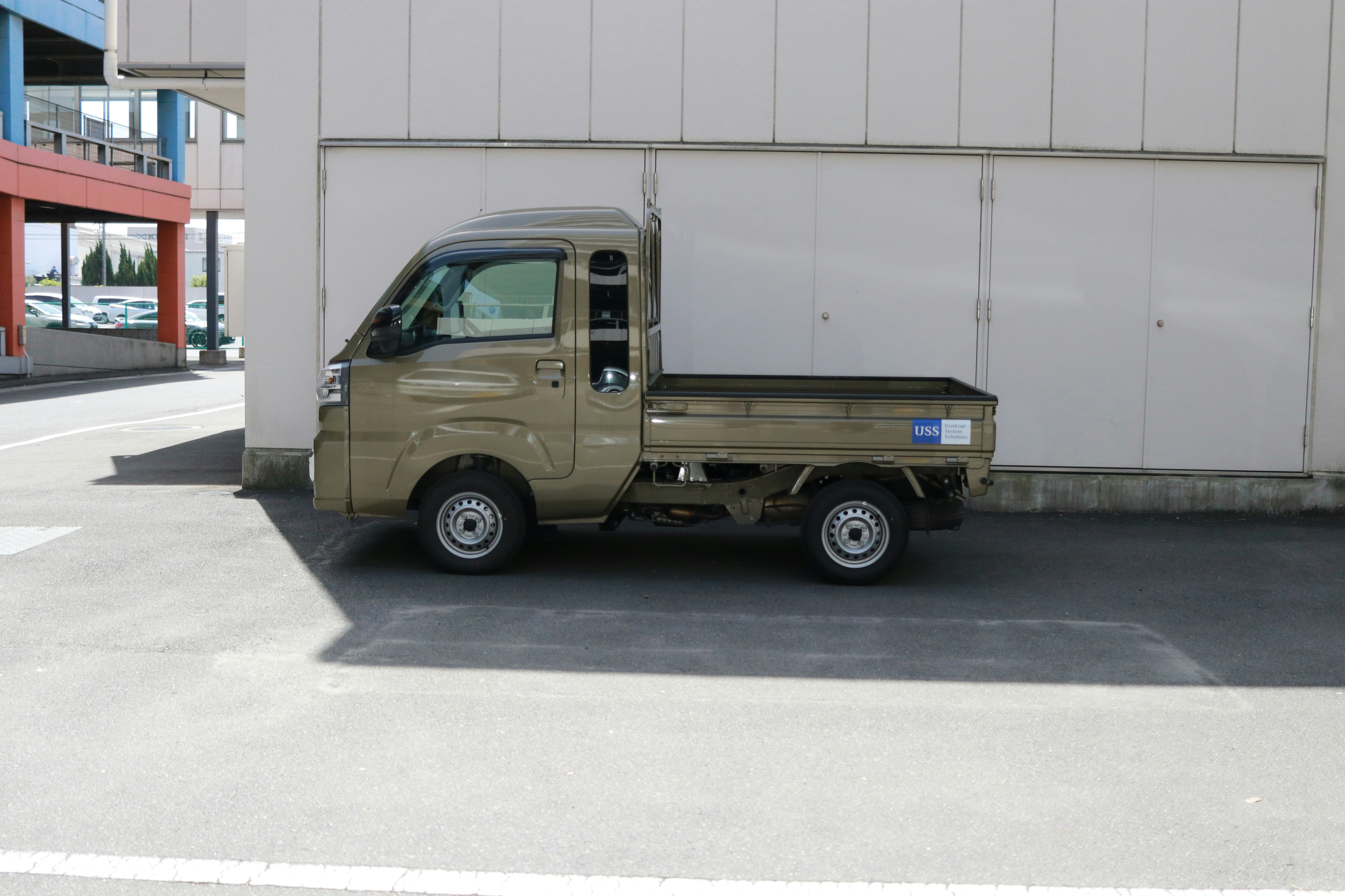 A small tan pickup truck is parked outdoors.