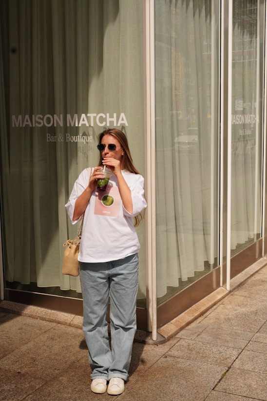 Woman enjoys a matcha drink outside a shop.