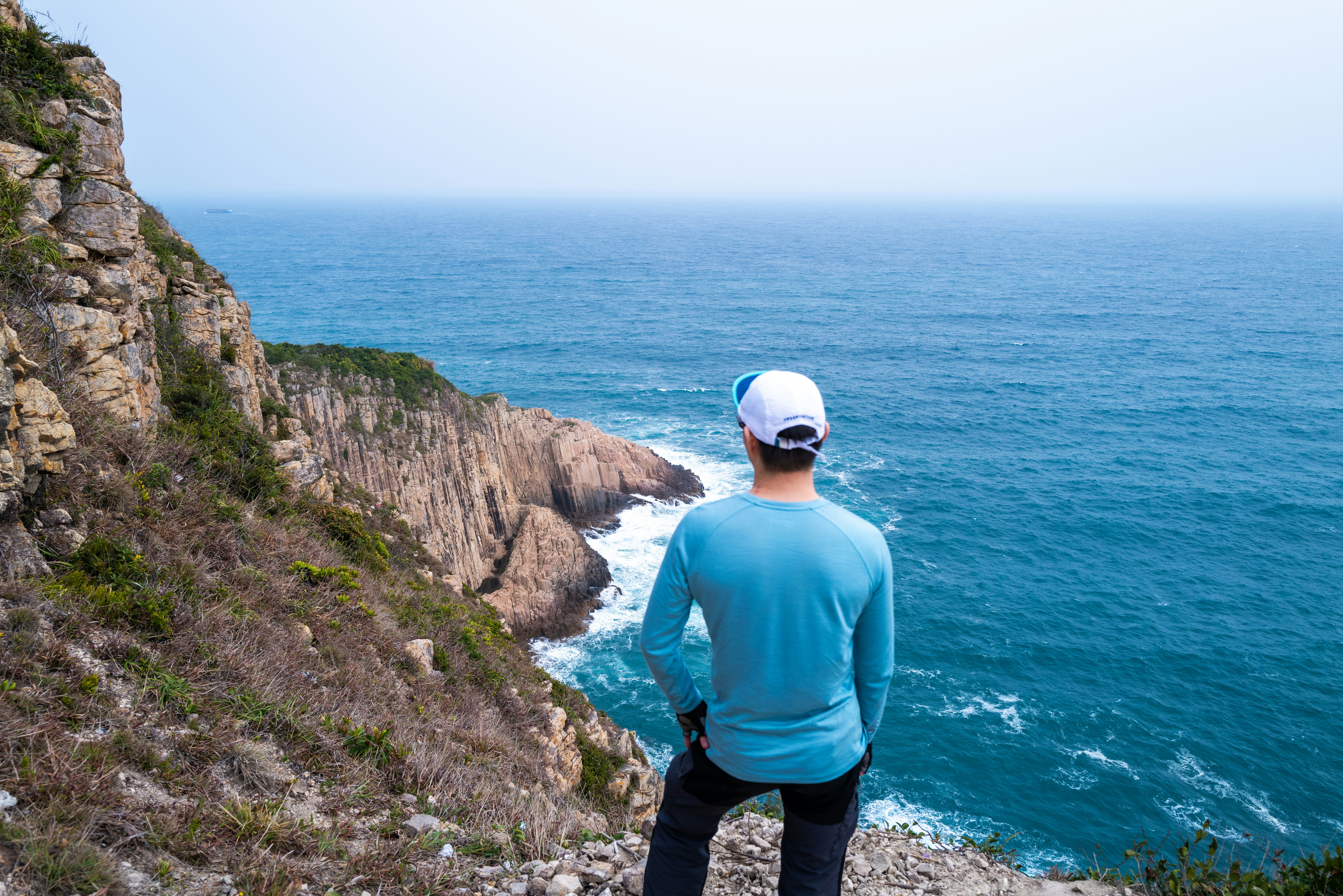 A person stands on a cliff edge, looking out at a bright, clear horizon, symbolizing a confident future achieved through strategic planning and protection - vip reputation management services