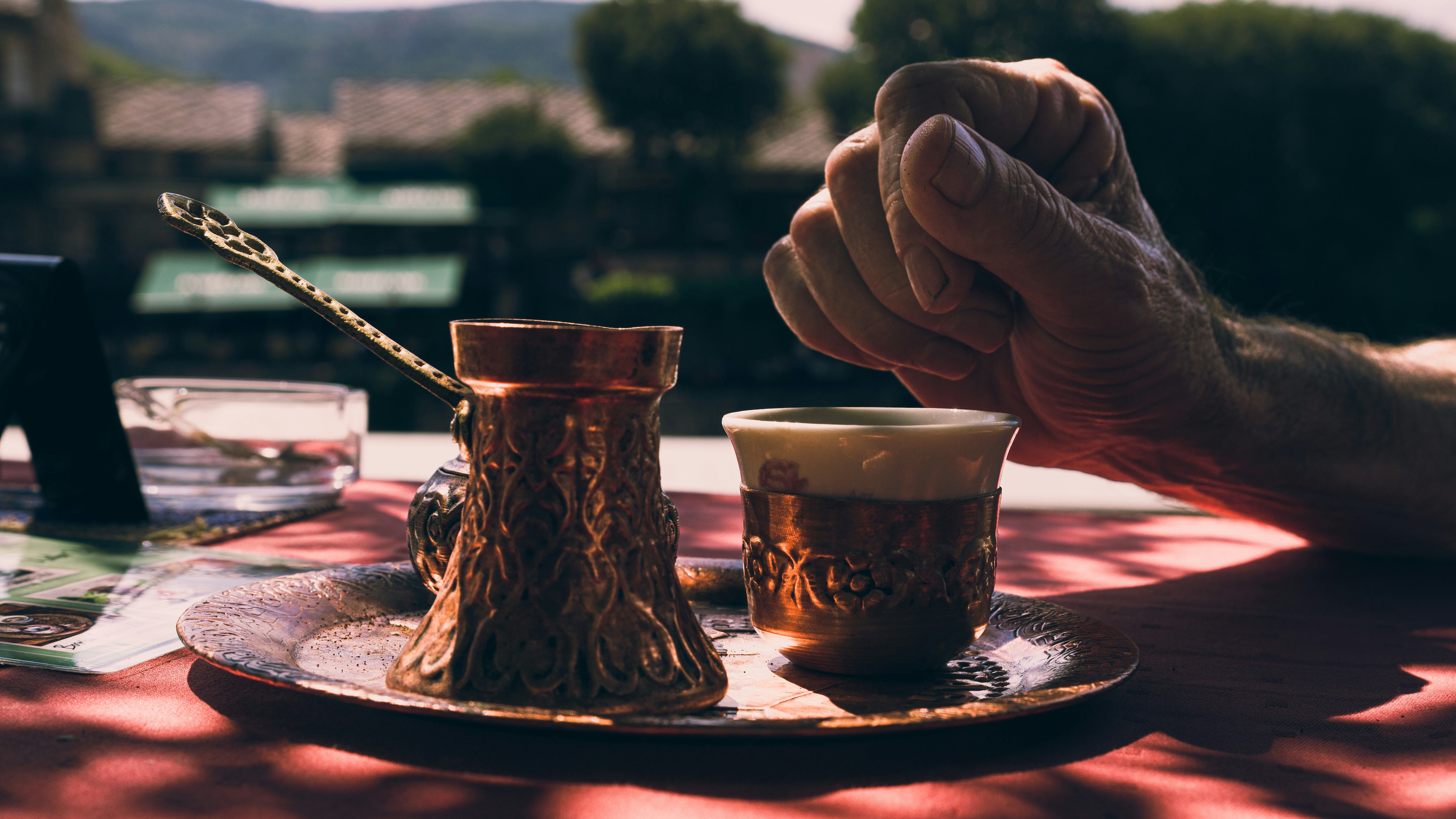 Coffee and hands sit on a table outdoors.