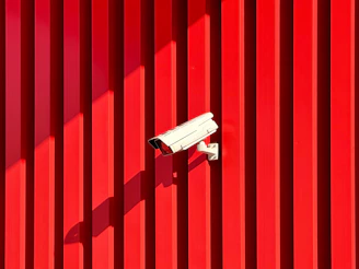 Cctv camera is mounted on a red wall