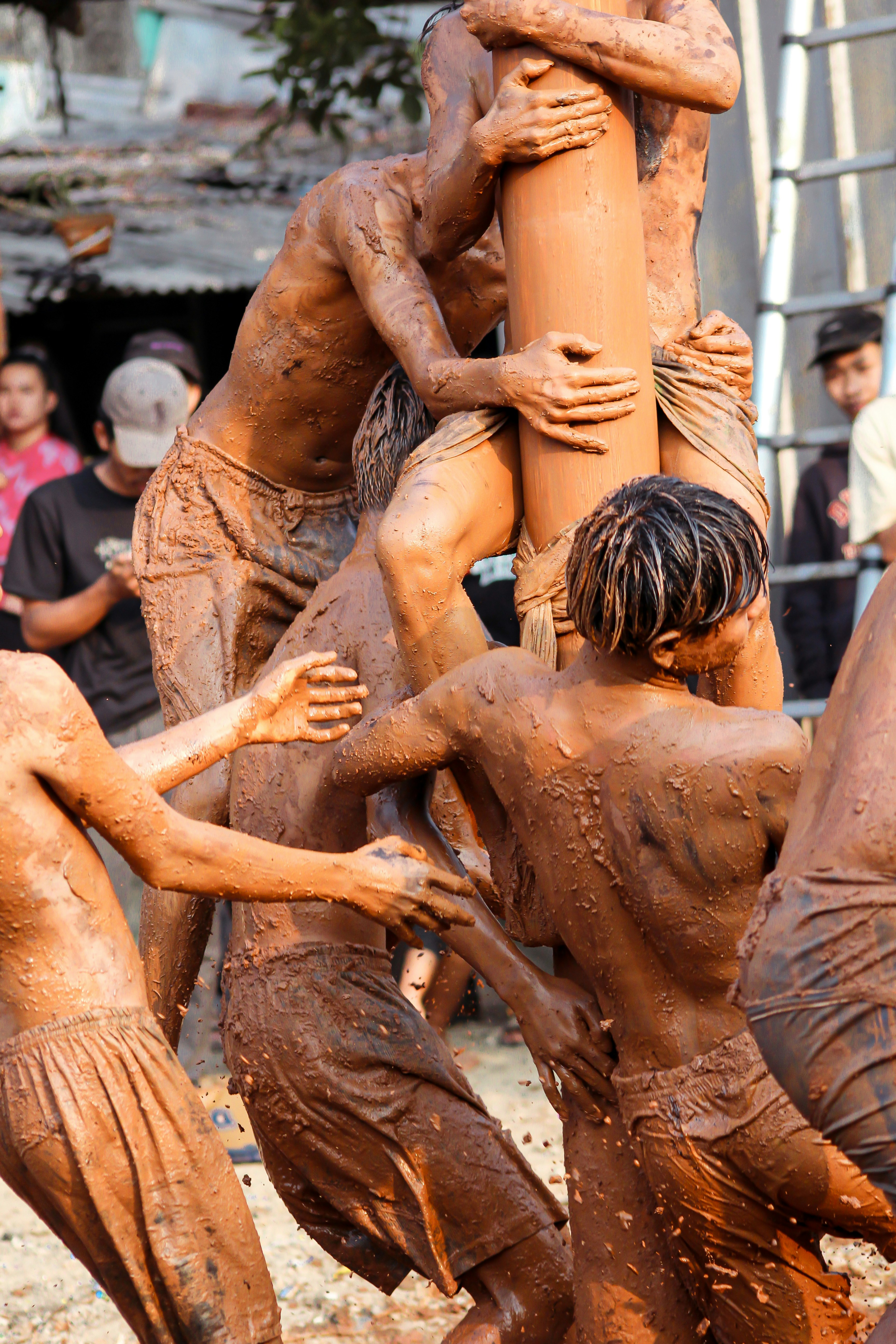 People covered in mud struggle to climb.
