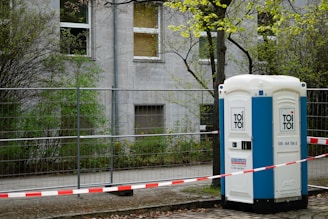 A portable toilet sits outside a building.