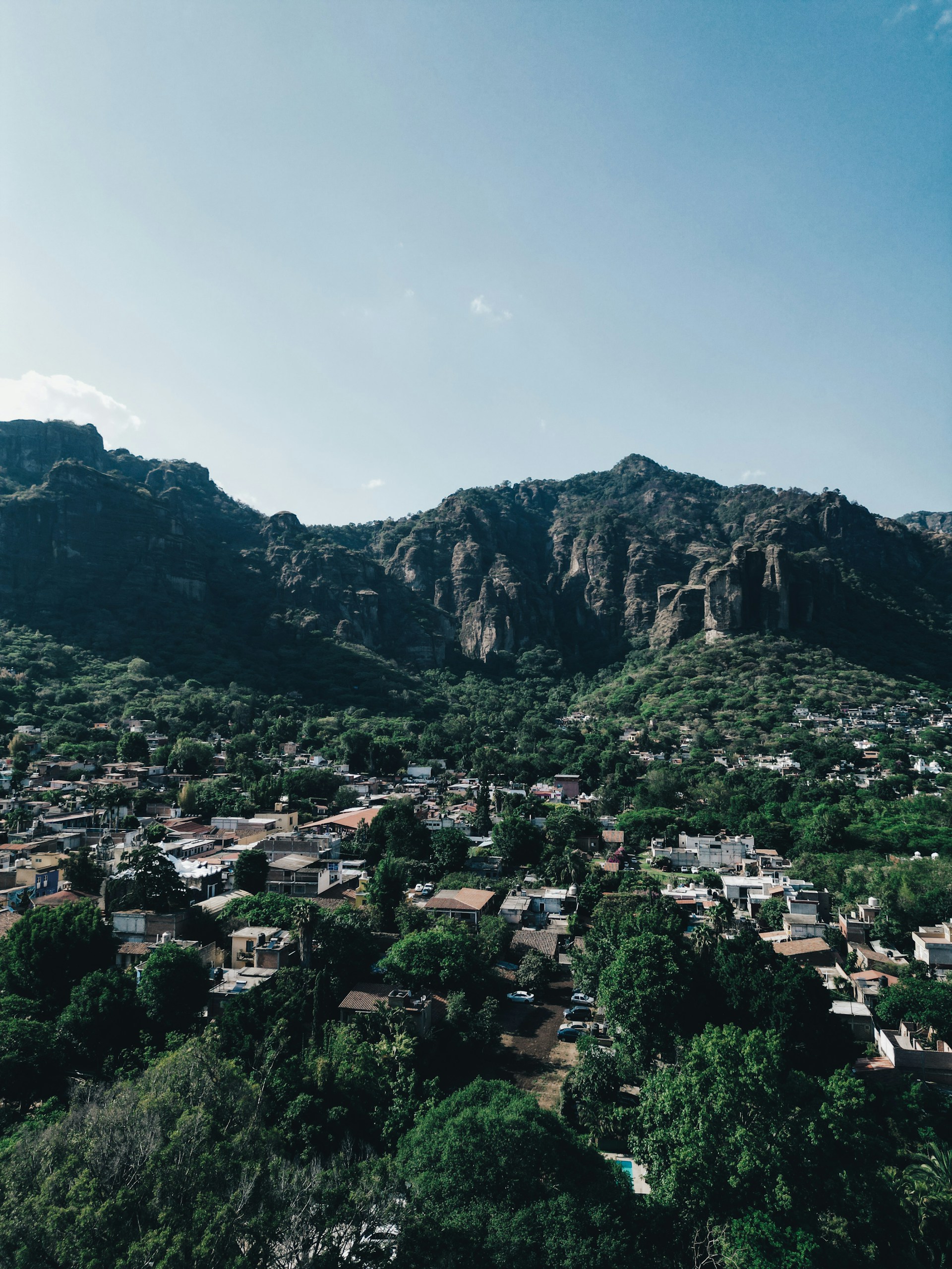 A lush valley town sits beneath tall mountains.