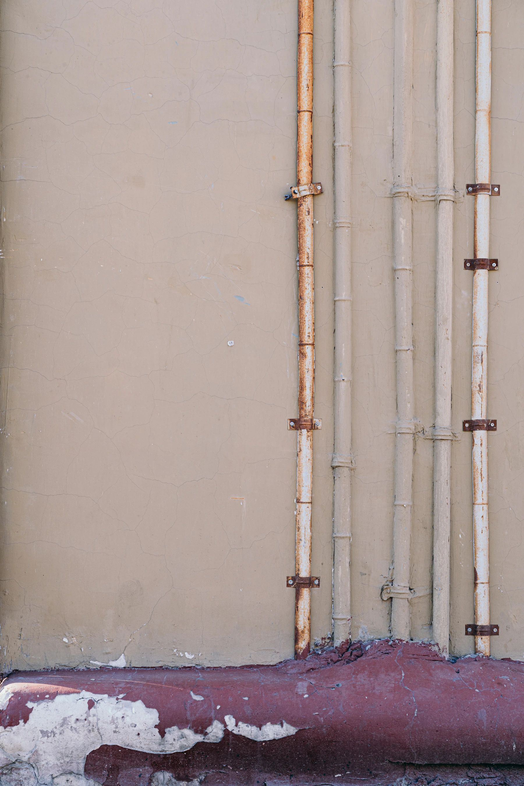 Copper and PVC supply lines run and clipped along a weathered stucco exterior wall