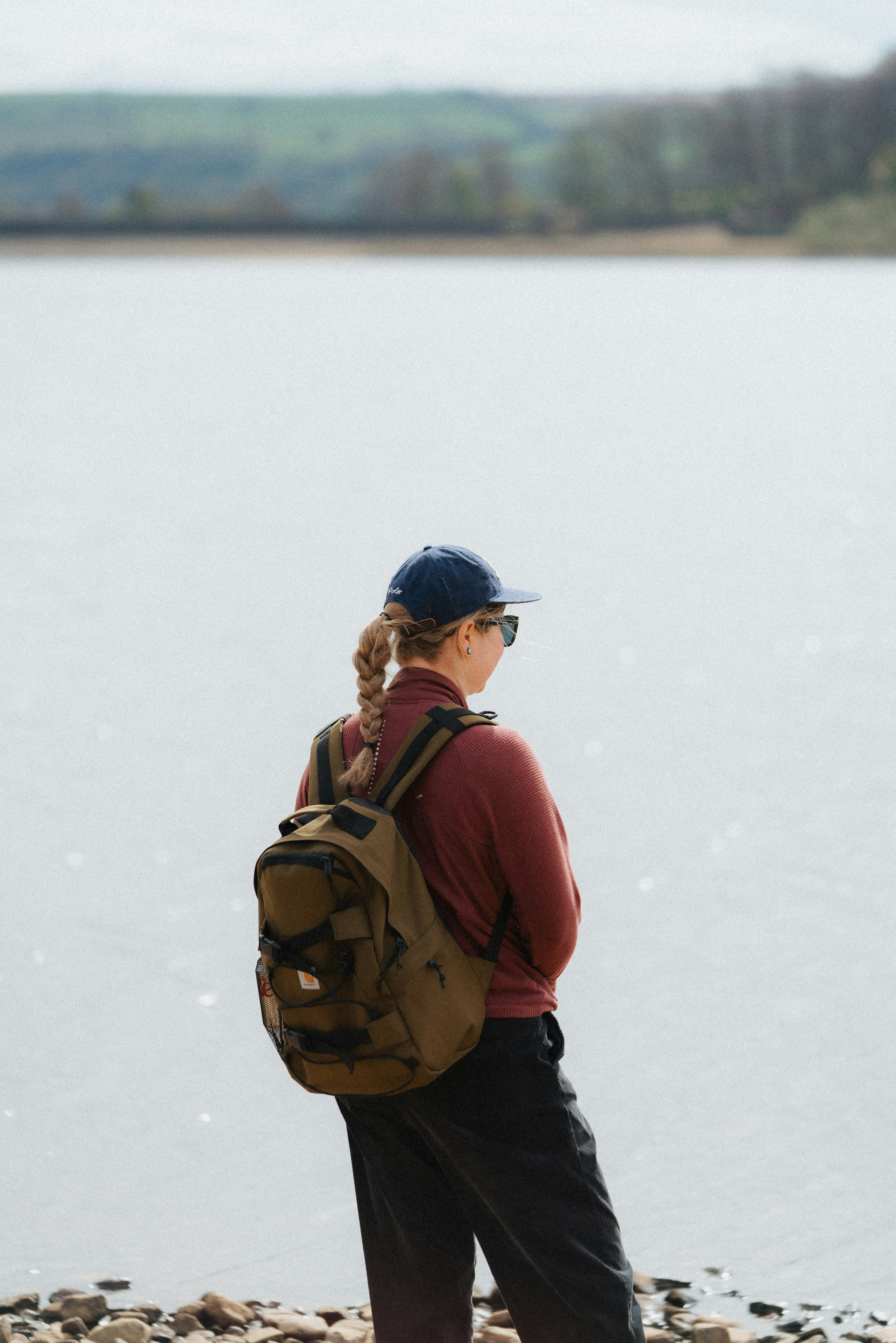 Uma mulher está à beira de um lago, contemplando.