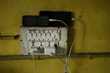 Phones are charging on an electrical outlet.
