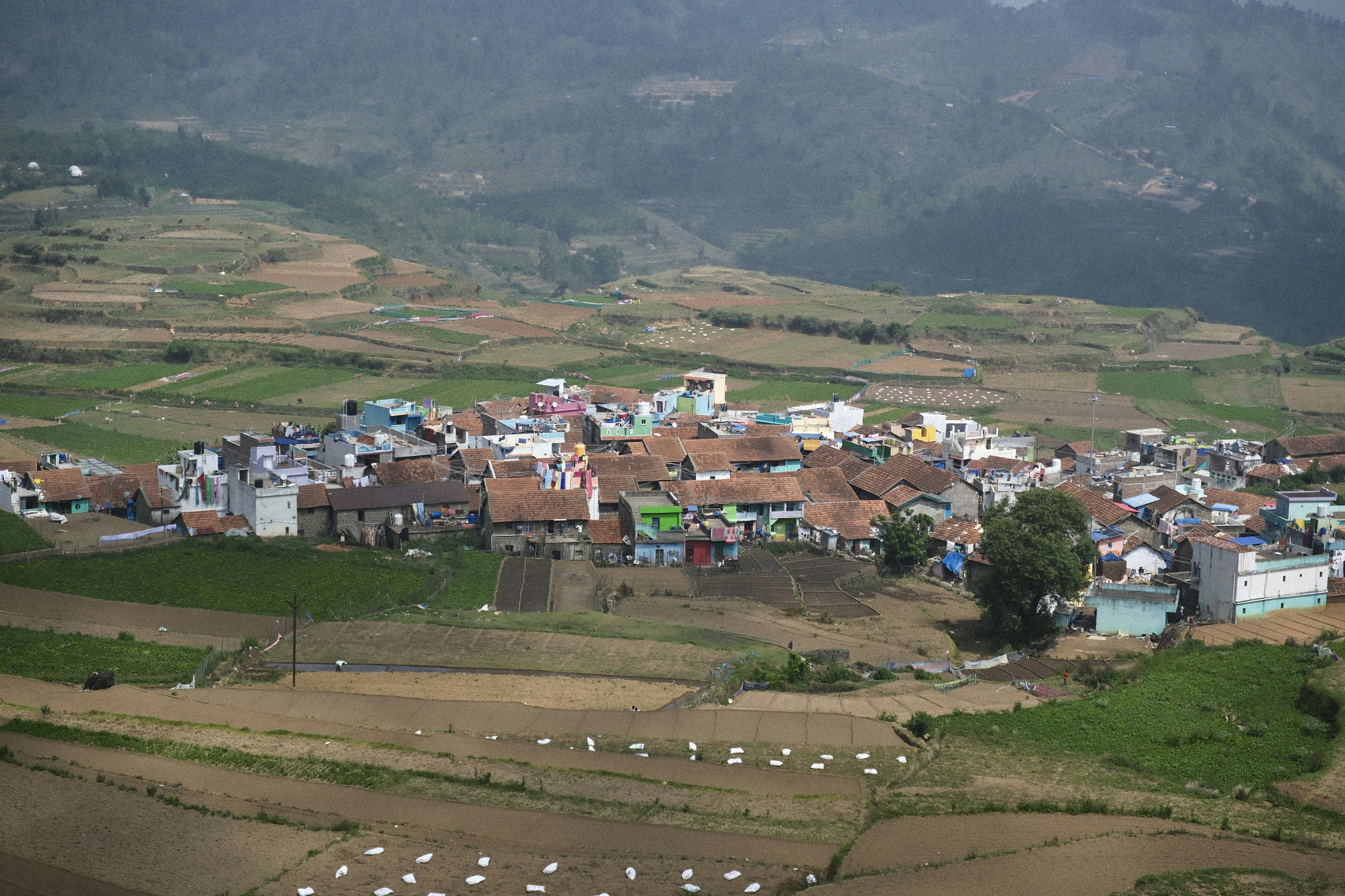 Village nestled in the mountains with surrounding fields.