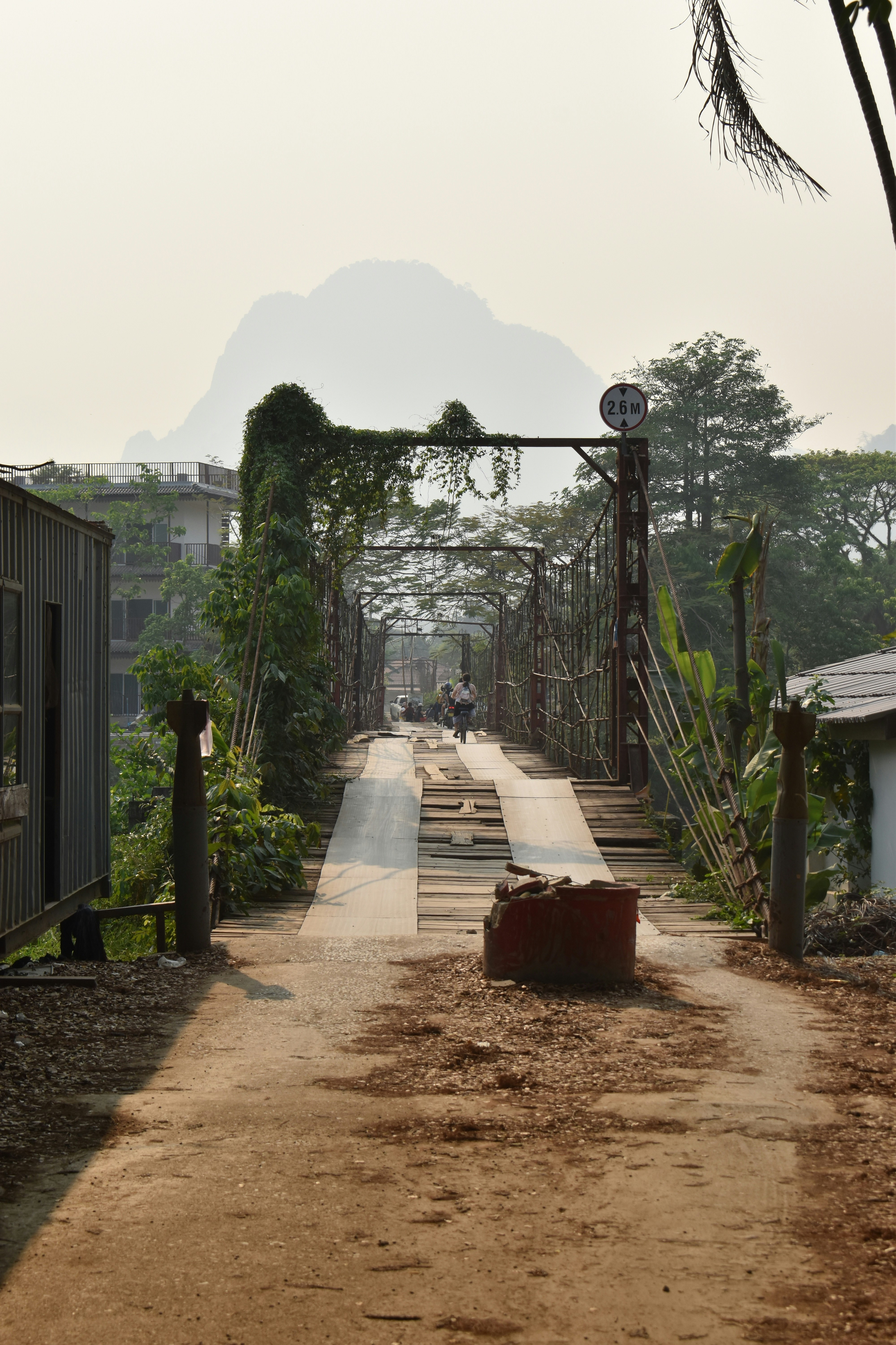 Sebuah jembatan mengarah ke gunung di kejauhan.