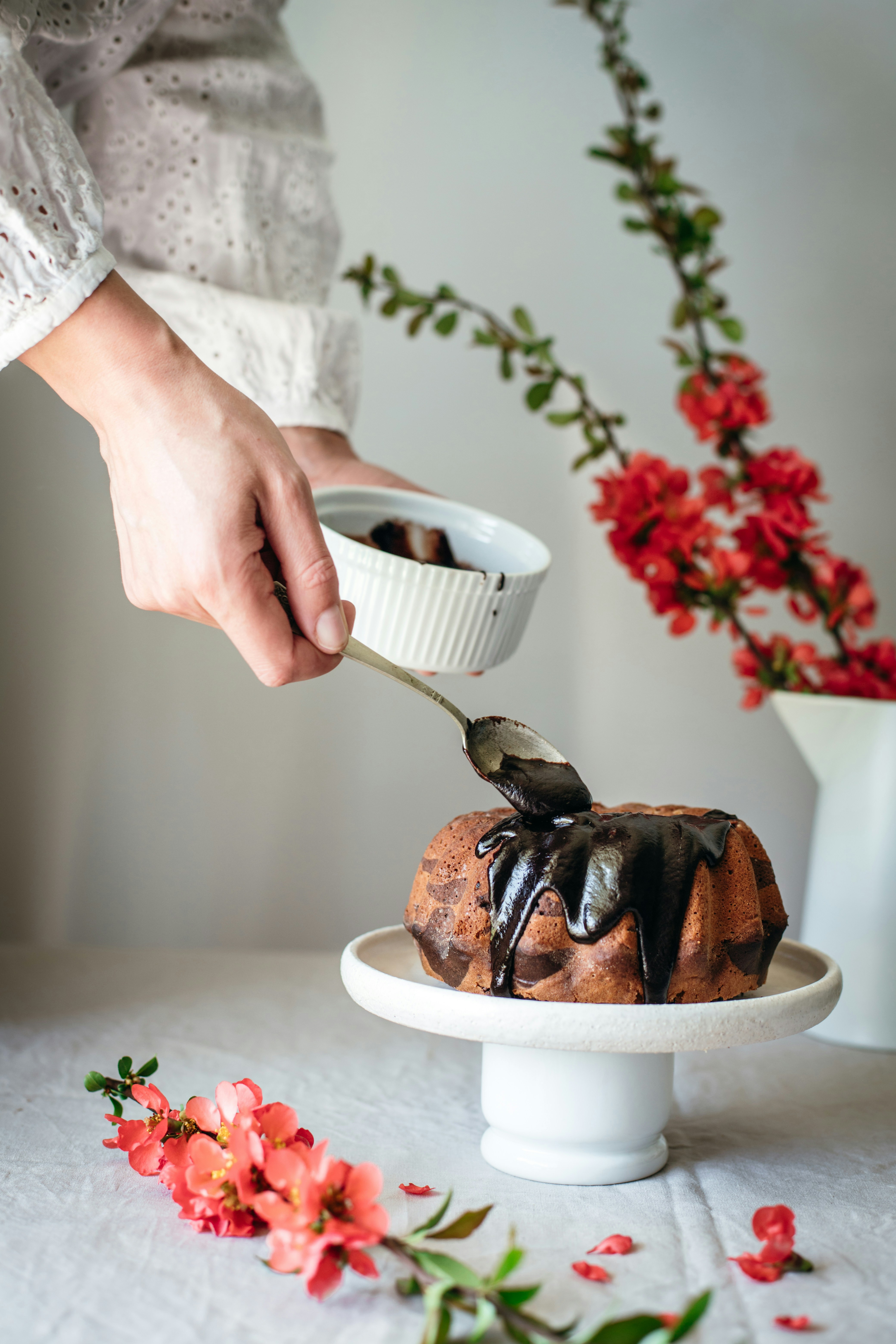 Someone is pouring chocolate ganache over a cake.