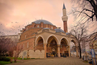 A mosque stands prominently against a cloudy sky.