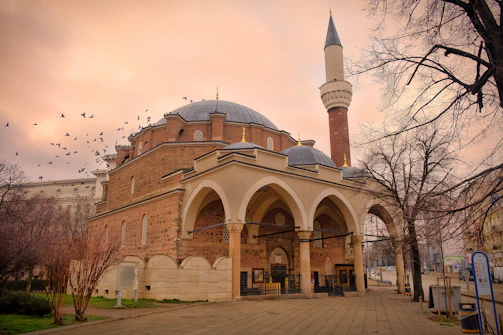 A mosque stands prominently against a cloudy sky.